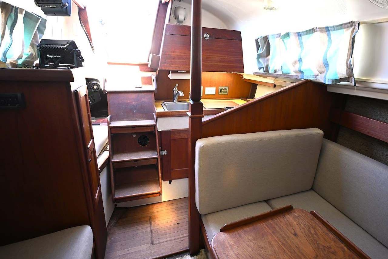 Interior of 1977 Mercator Offshore boat with wooden furnishings and compact kitchen area.