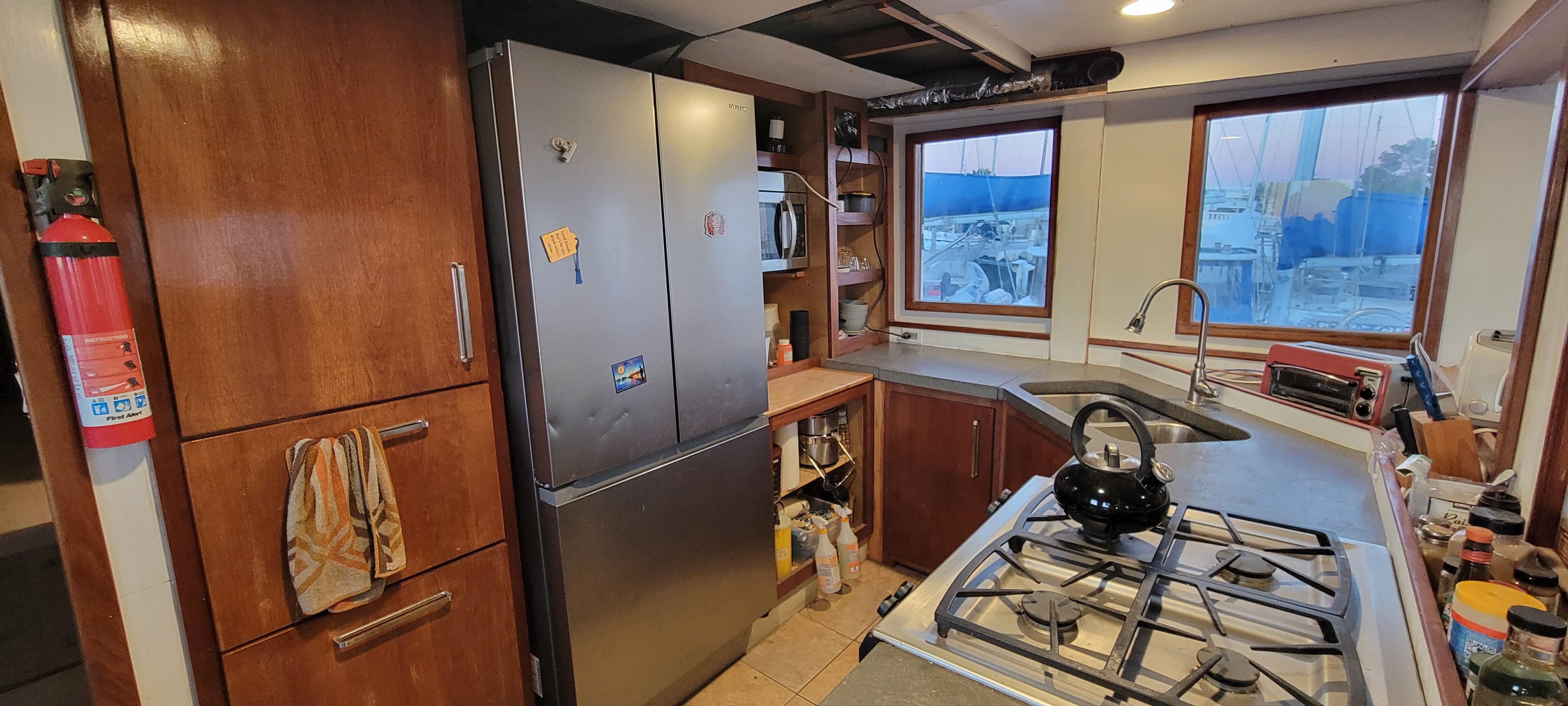 1979 Shrimper Conversion Trawler kitchen with stainless steel appliances and wooden cabinetry.