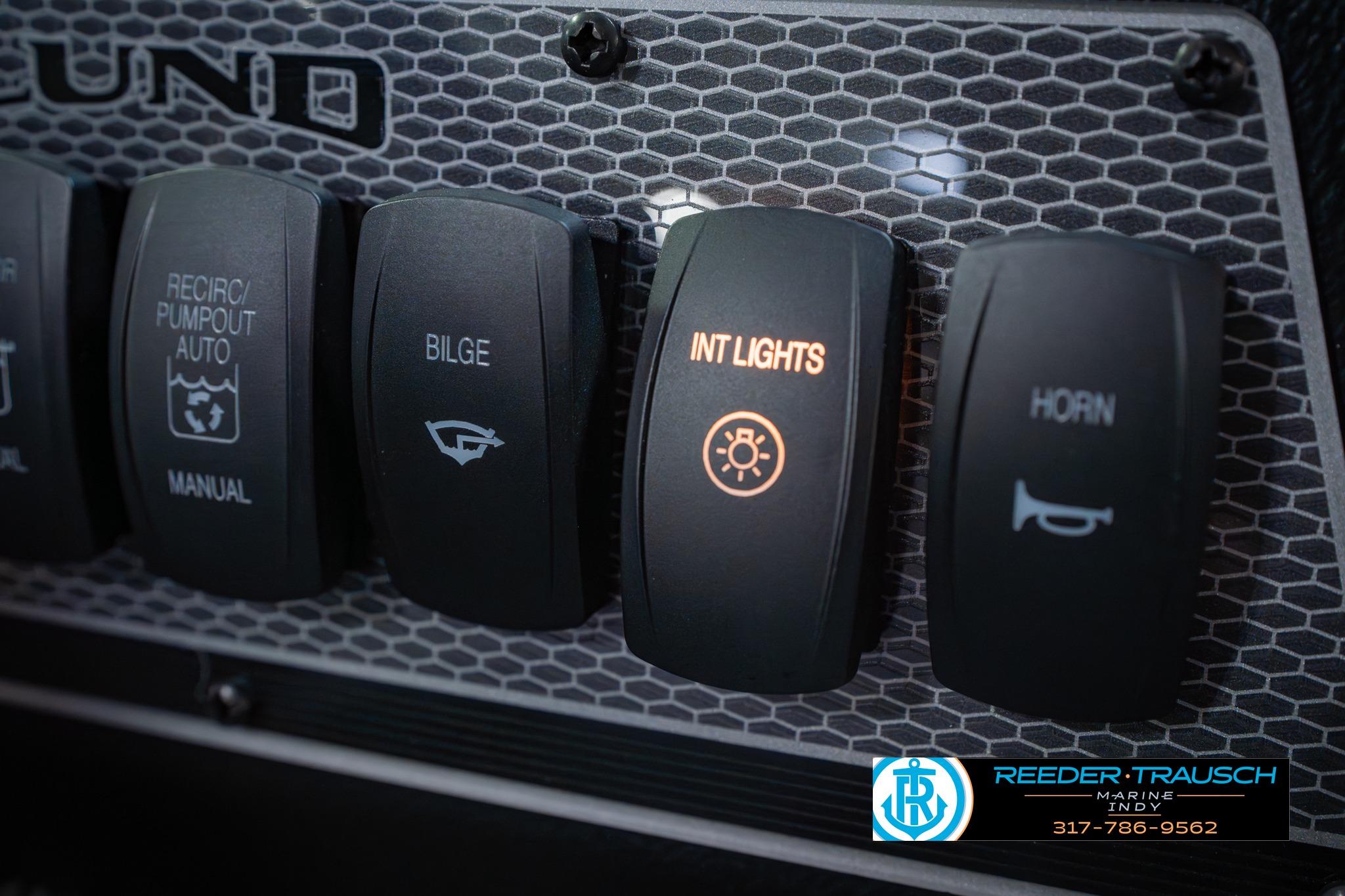 Control panel of 2026 Lund 1875 Impact XS boat with illuminated interior lights switch.