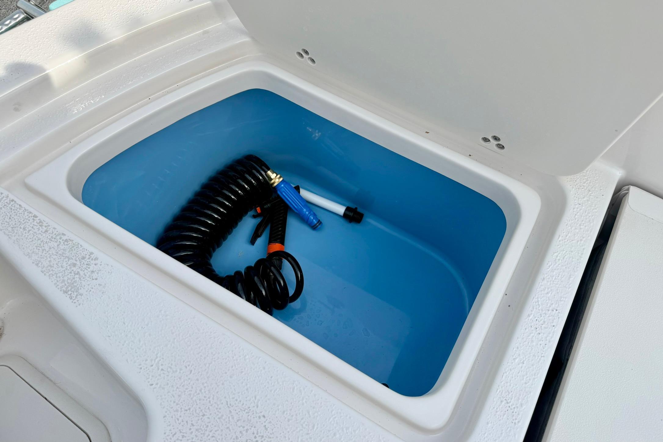 Storage compartment with coiled hose on 2026 Carolina Skiff 24 Ultra Elite boat.