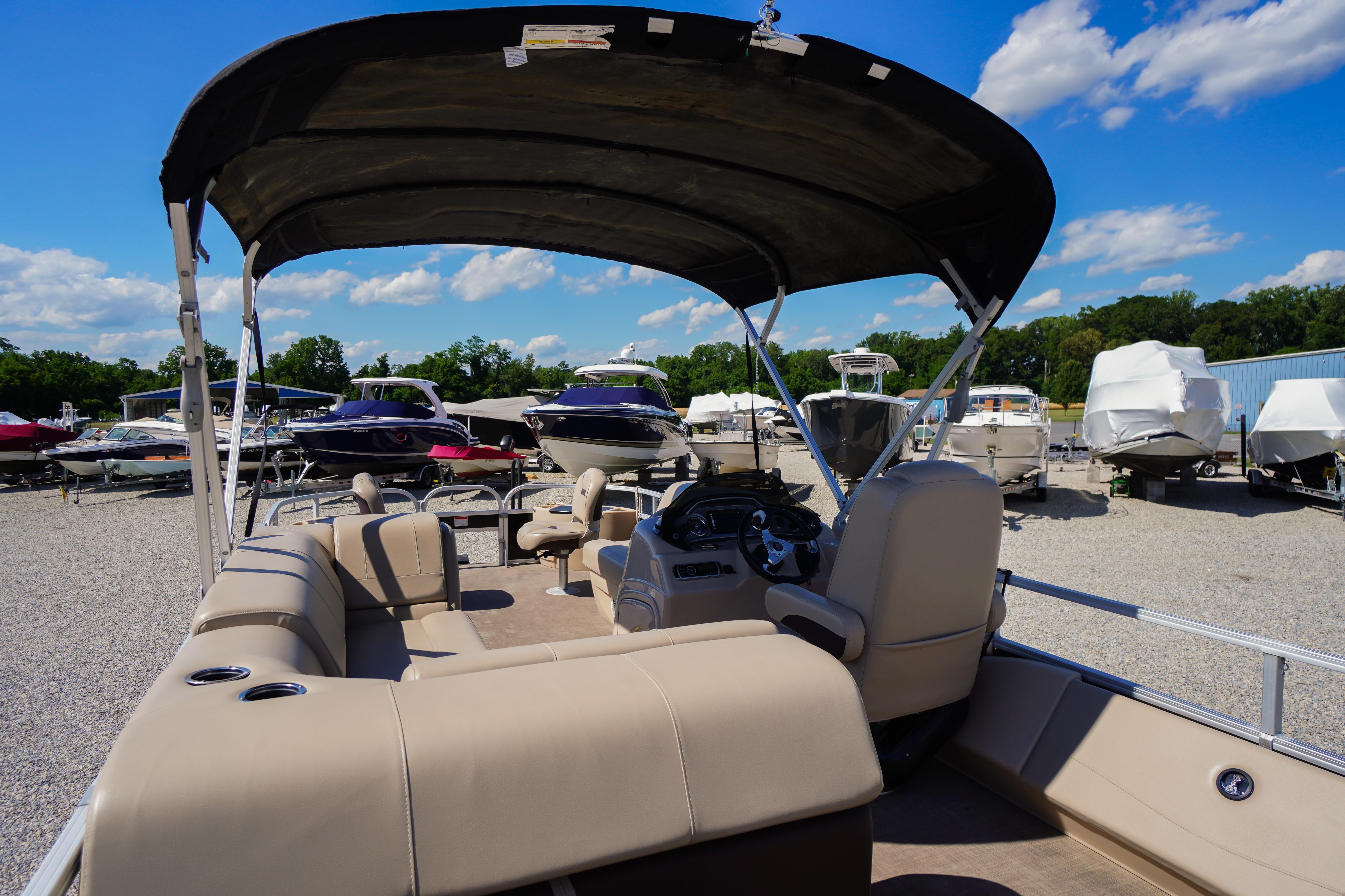 2019 SUNTRACKER Fishin' Barge 22 DLX pontoon boat with canopy in a boatyard.