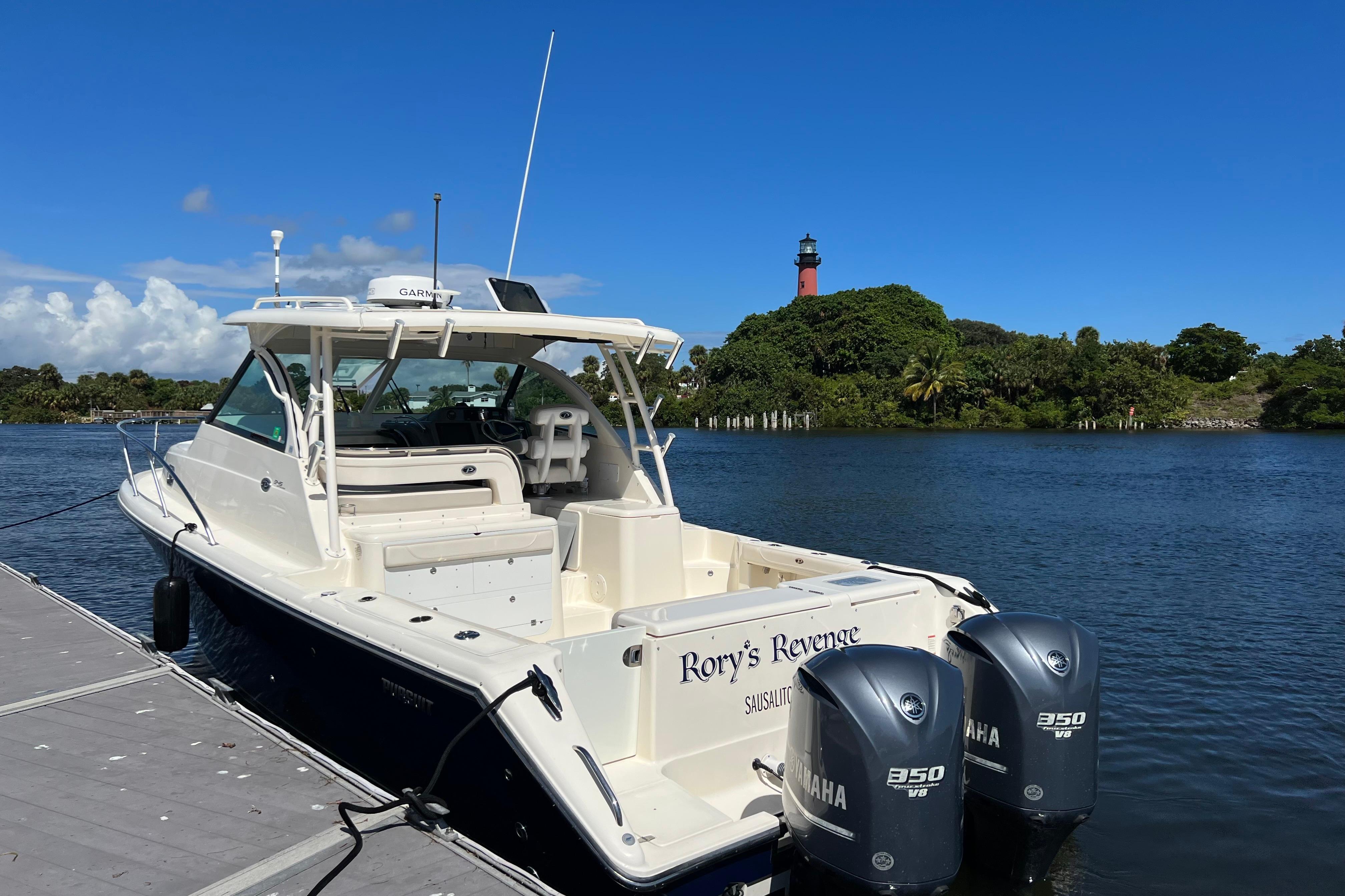 2014 Pursuit OS 345 Offshore boat docked by a scenic lighthouse.