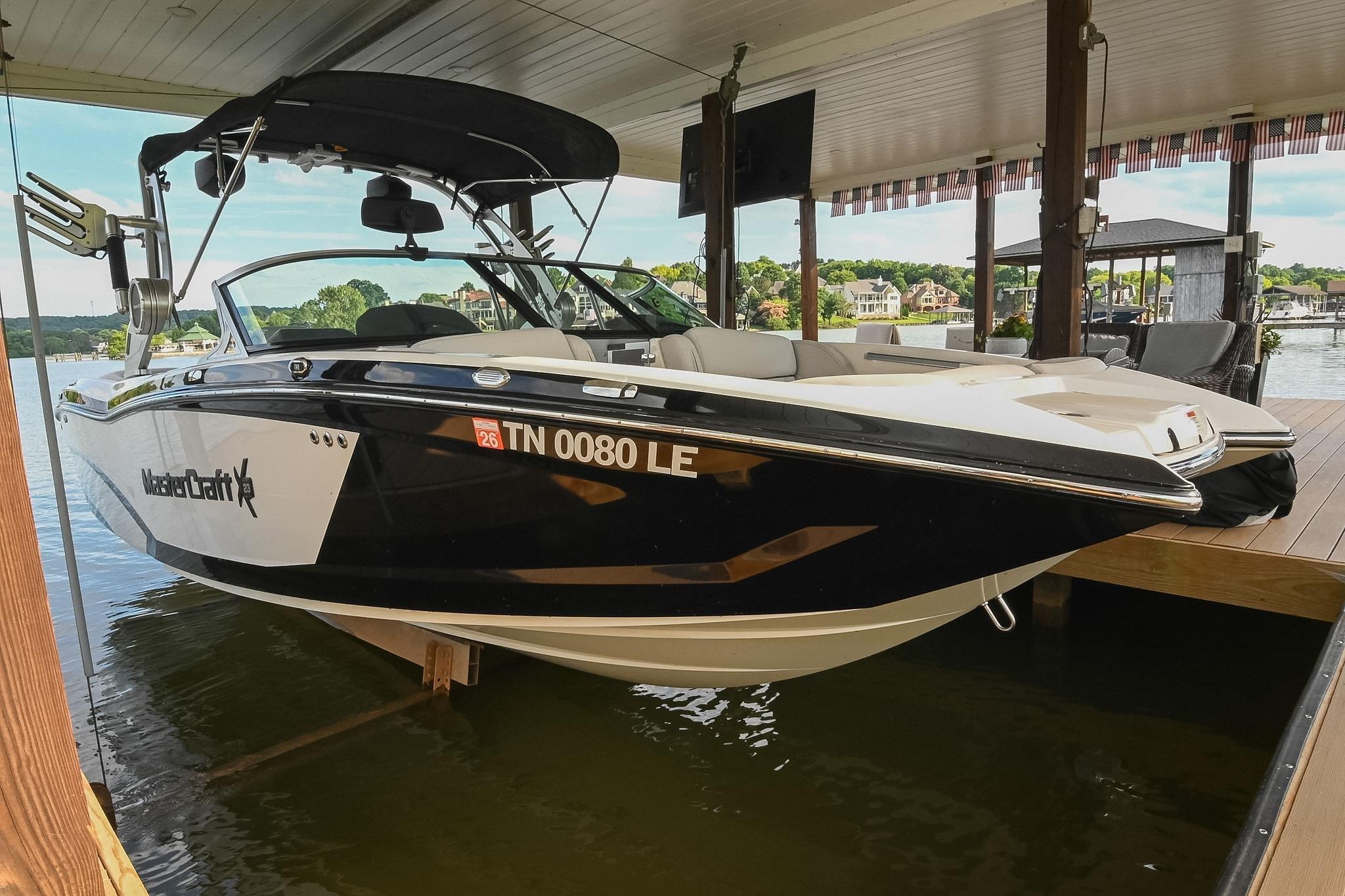 2018 MasterCraft X23 boat docked under a covered marina on a sunny day.