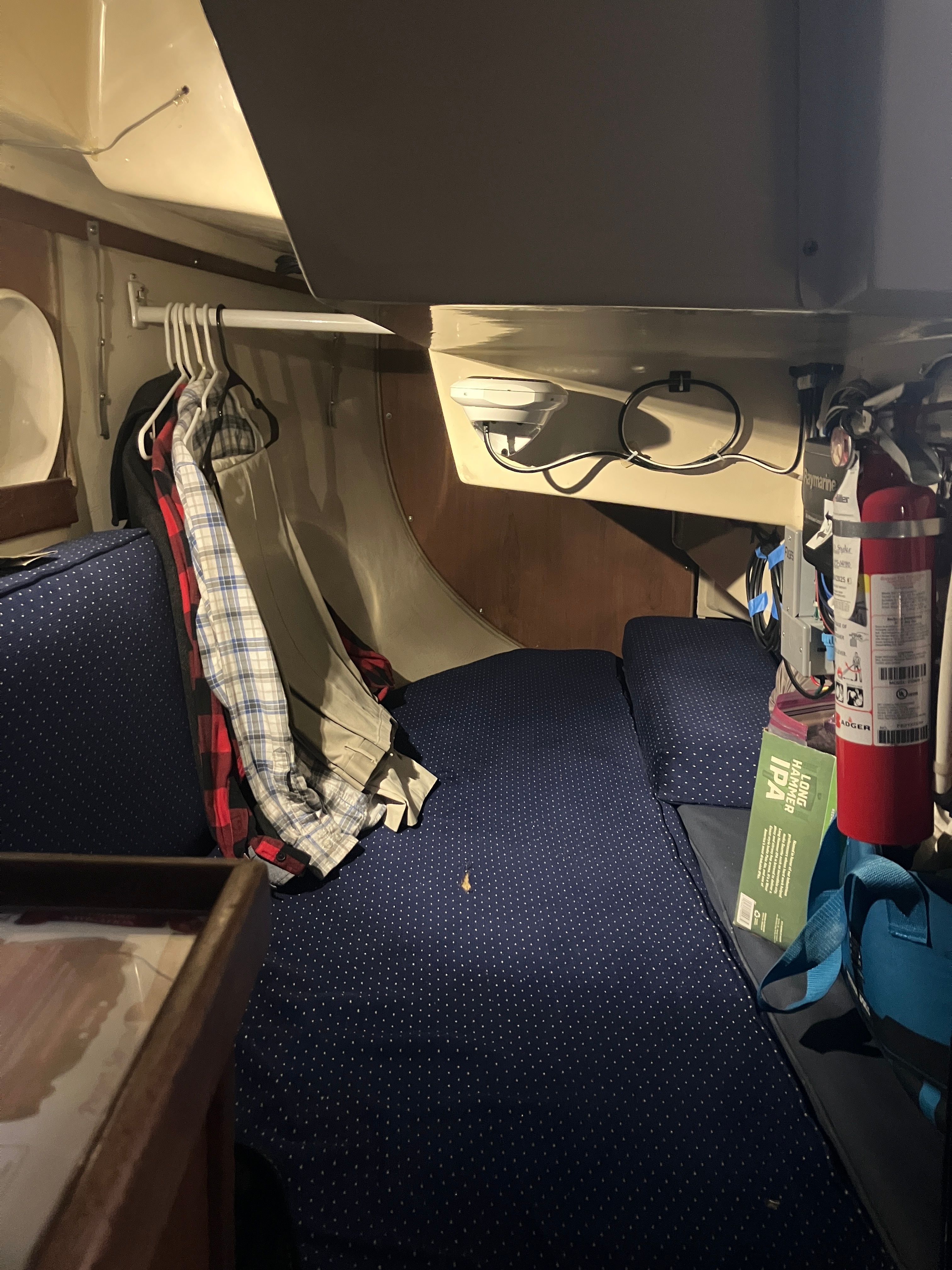 Interior of a 1984 Catalina 30 with blue upholstery and clothes hanging on a rack.