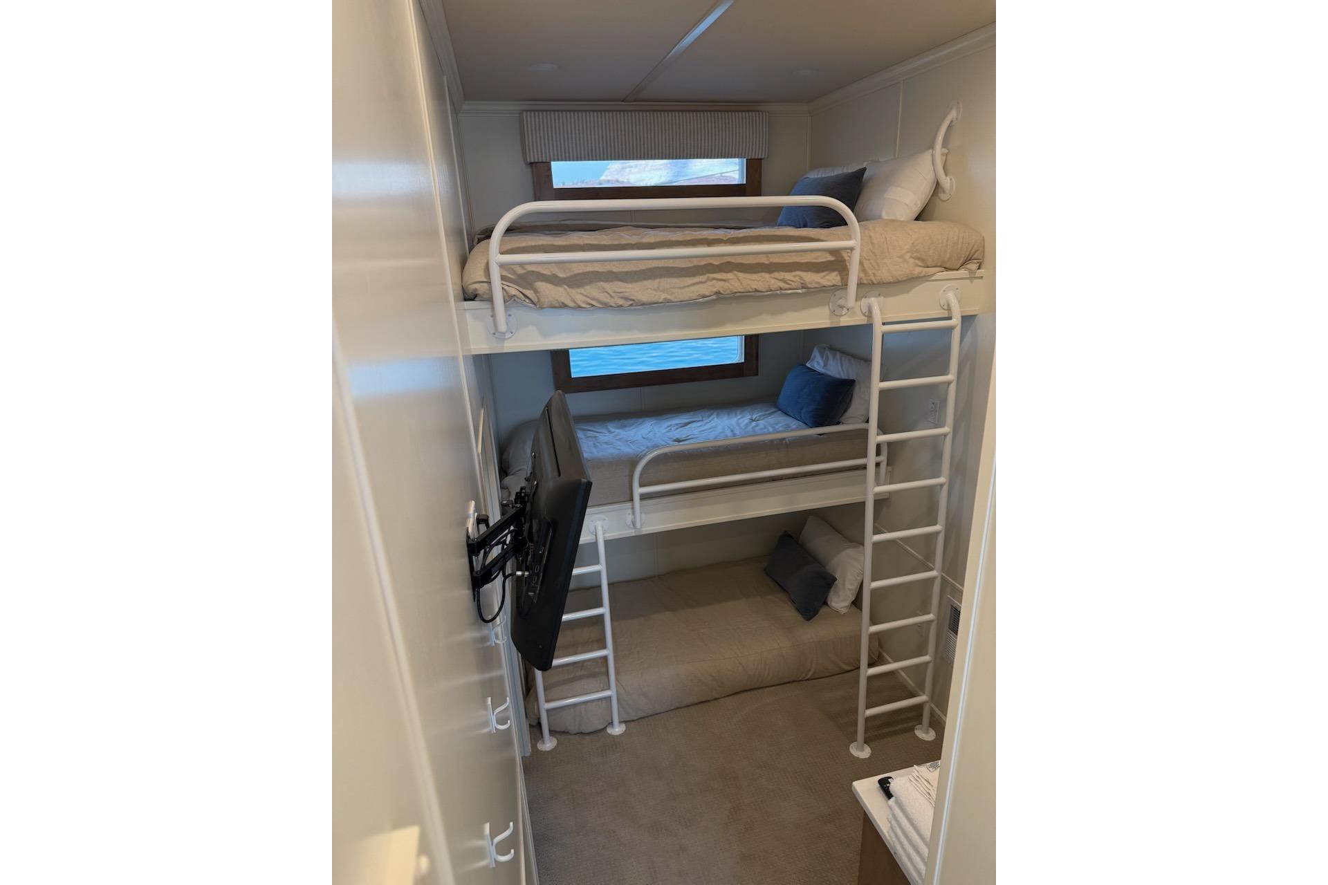 Bunk beds in 2025 Sumerset Relentless Multiple Shares houseboat cabin, featuring a TV and window view.