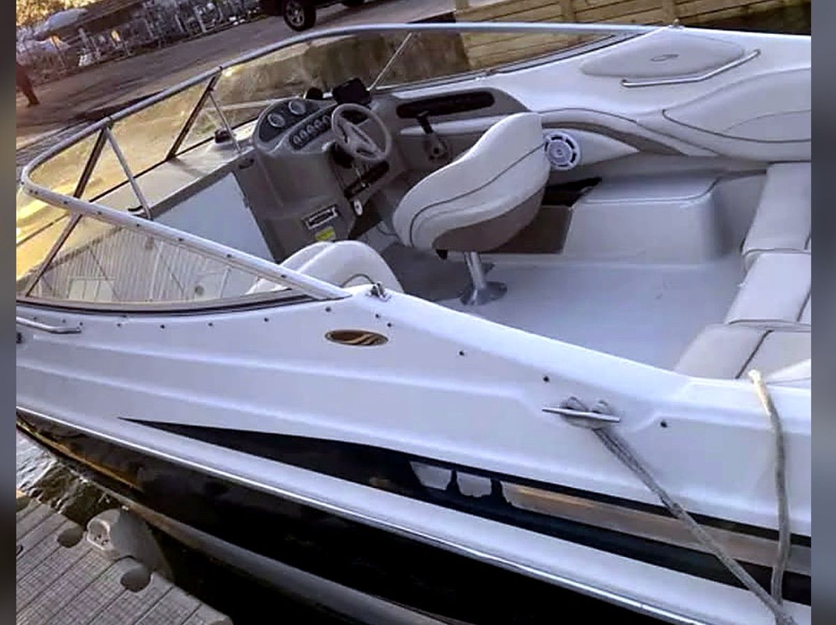 A 1999 Maxum 2300CC boat with a white and black hull, cockpit, and helm station.