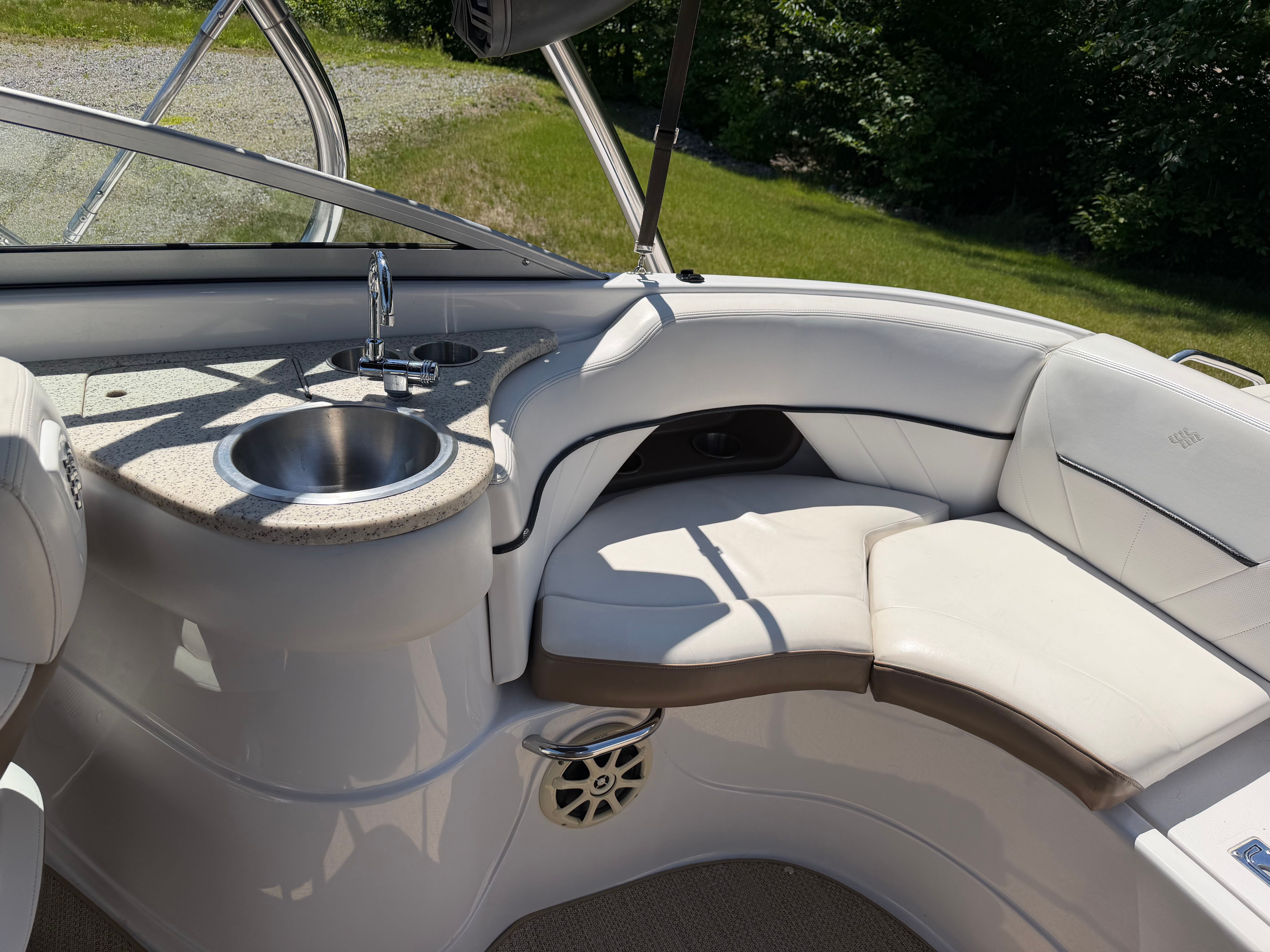 The image shows the cockpit of a 2008 Four Winns H240 Frenzy boat with white seating and a sink.