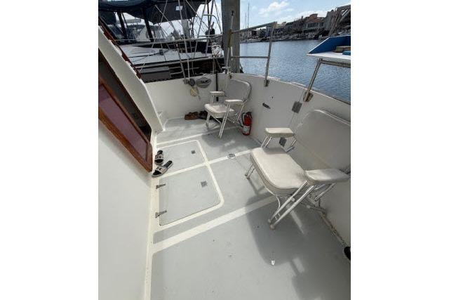 1982 Lancer 45 Motorsailer cockpit with folding chairs, docked by the water.