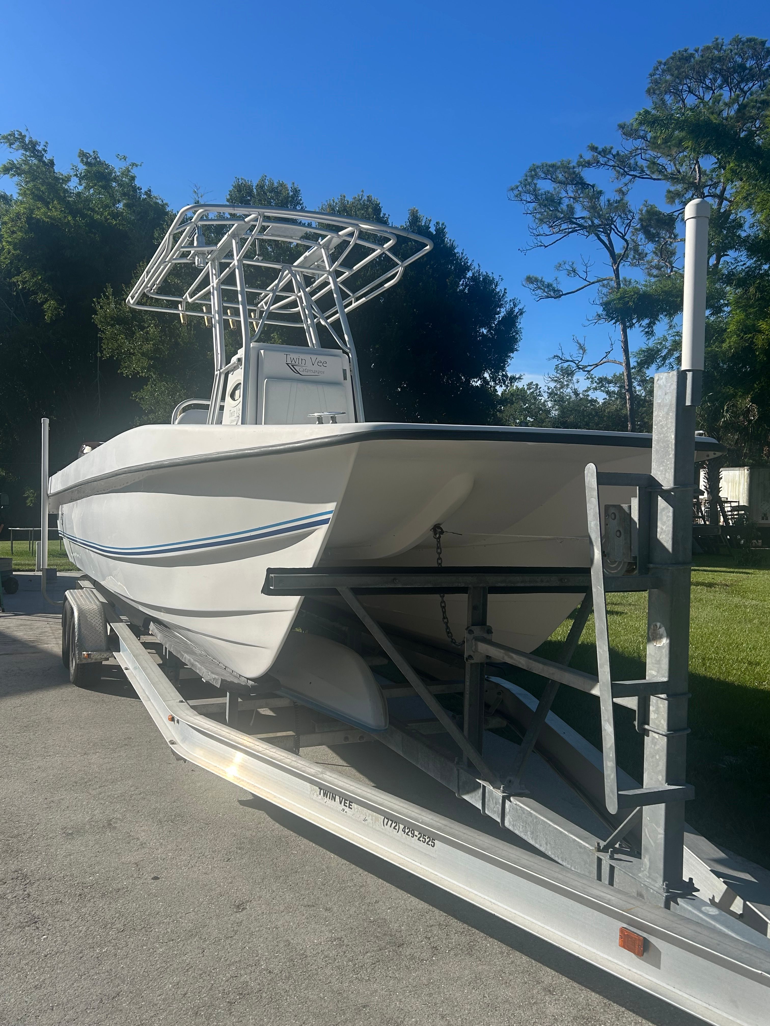 A white 2007 Twin Vee 26 Center Console boat is on a trailer outdoors.