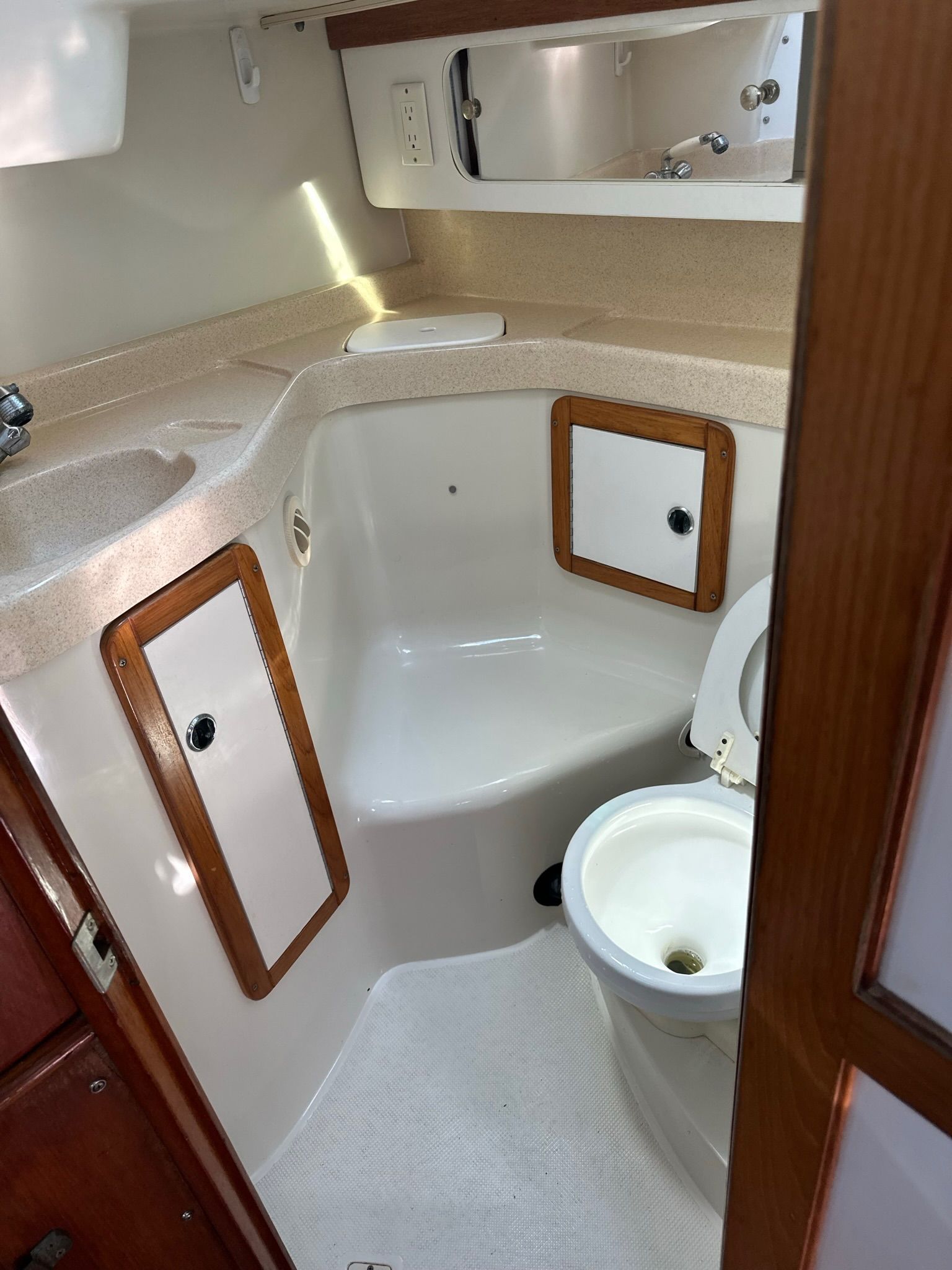 The image shows a boat bathroom with a toilet, sink, and storage compartments.