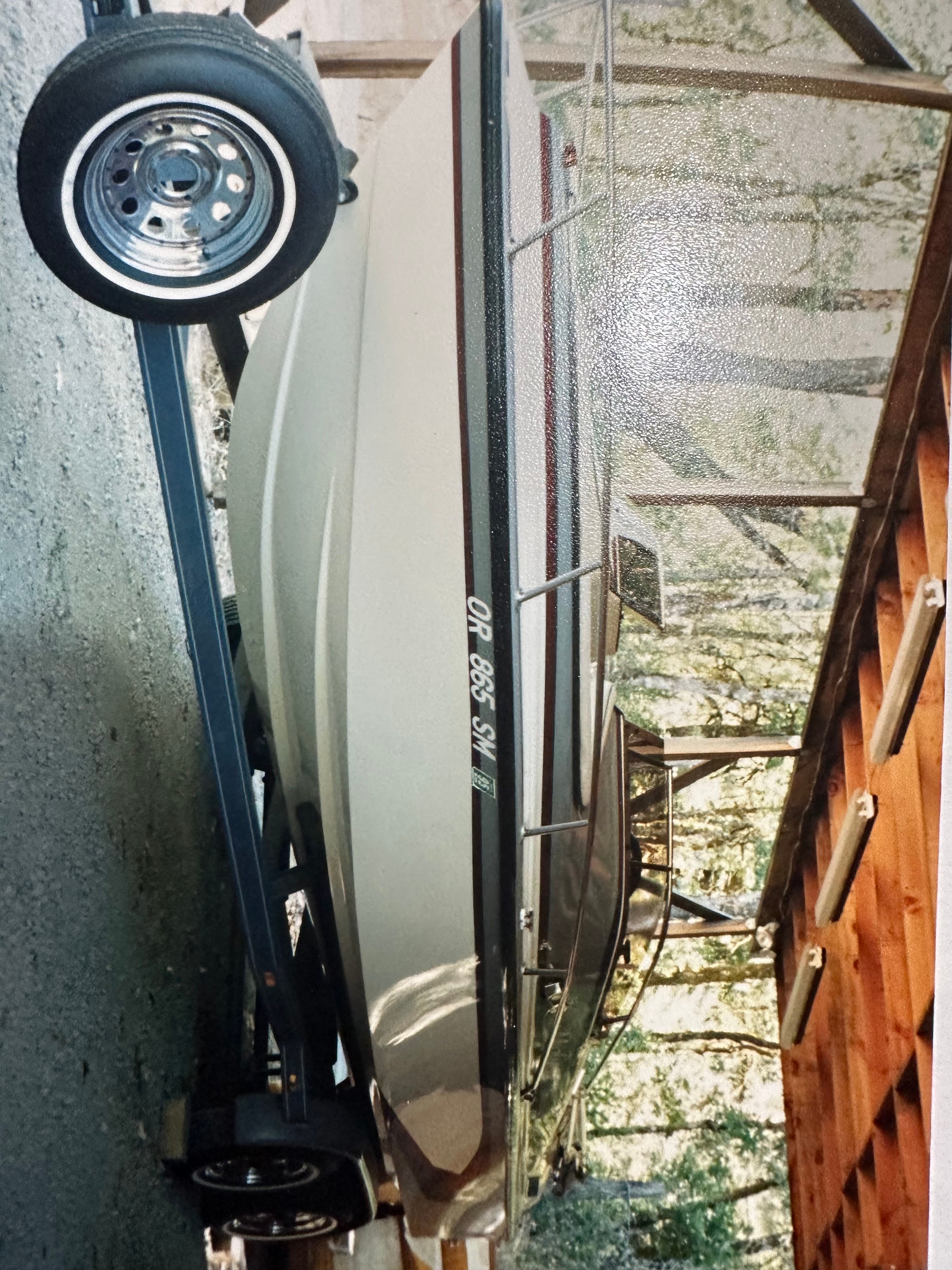 A 1990 Marlin Open Bow boat on a trailer in a covered area.