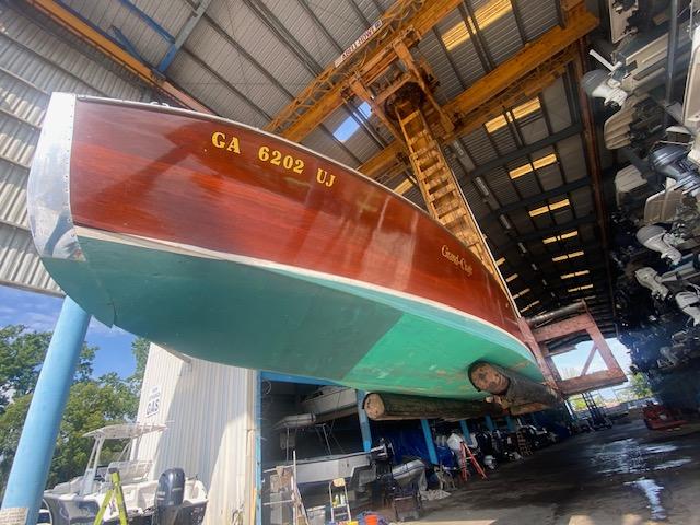 Grand Craft Classic Runabout 2000 in a boatyard, suspended for maintenance.