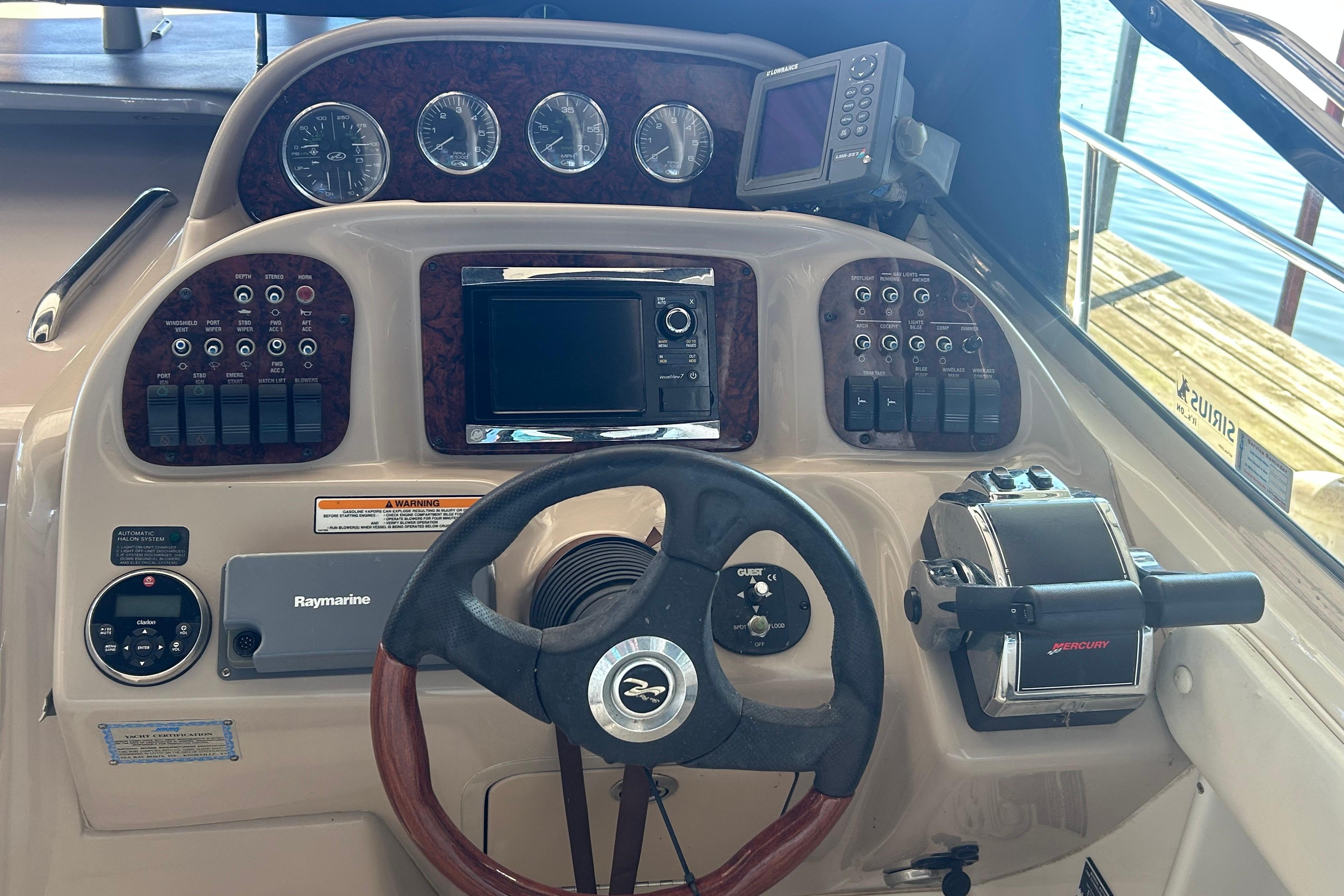 Control panel of a 2005 Sea Ray 300 Sundancer boat with steering wheel and navigation instruments.