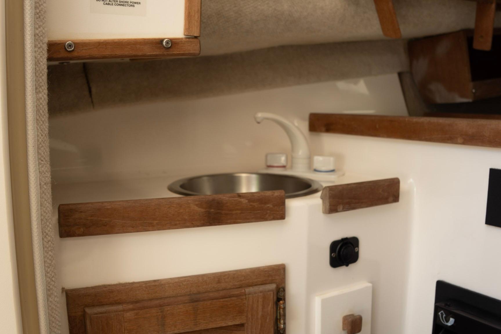 2006 Atlas Boat Works Acadia 25 interior with compact sink and wooden cabinetry.