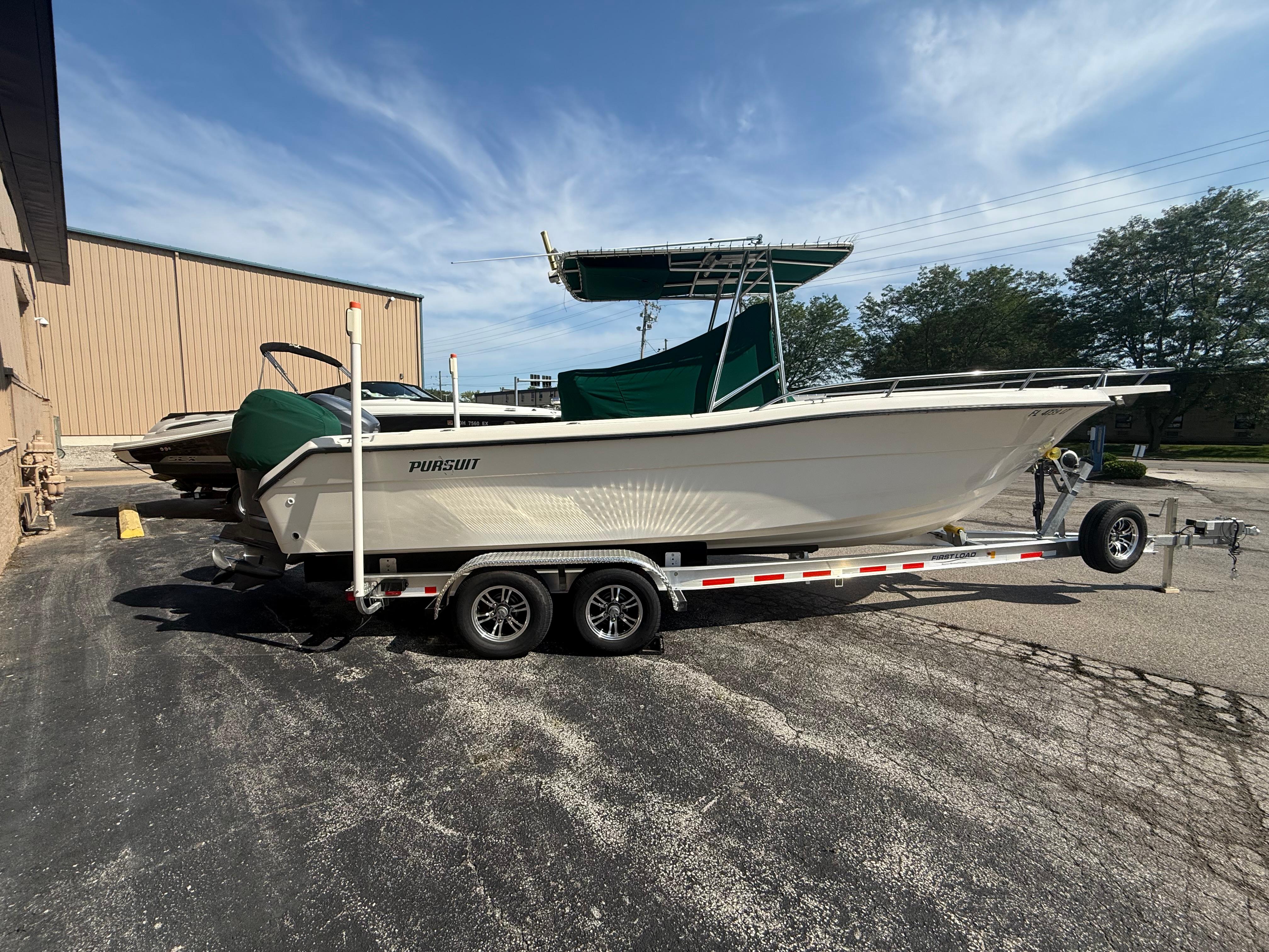2002 Pursuit 2470 CC boat on trailer, parked outdoors under a clear sky.