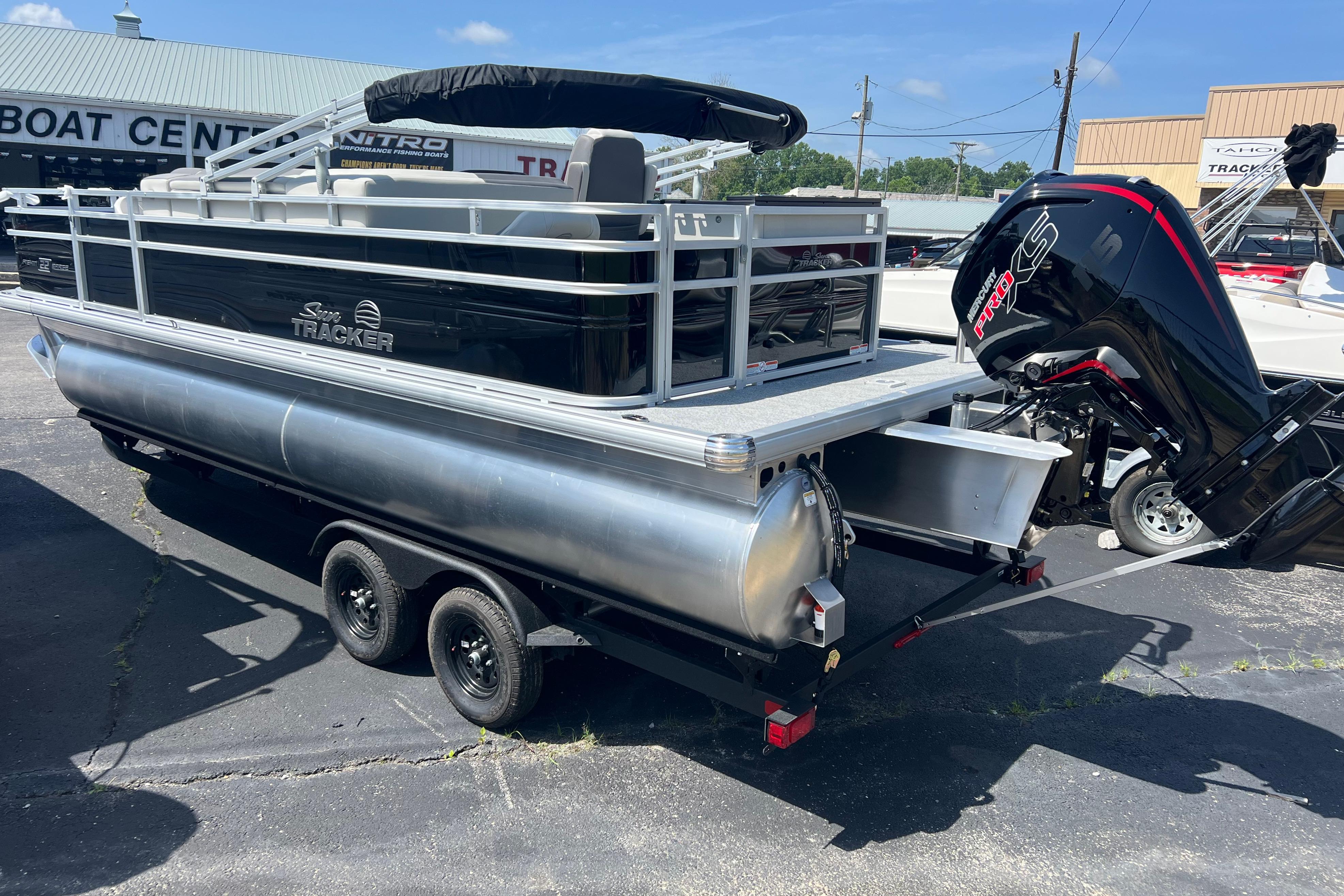2026 Sun Tracker Fishin' Barge 22 DLX pontoon boat on trailer at dealership.