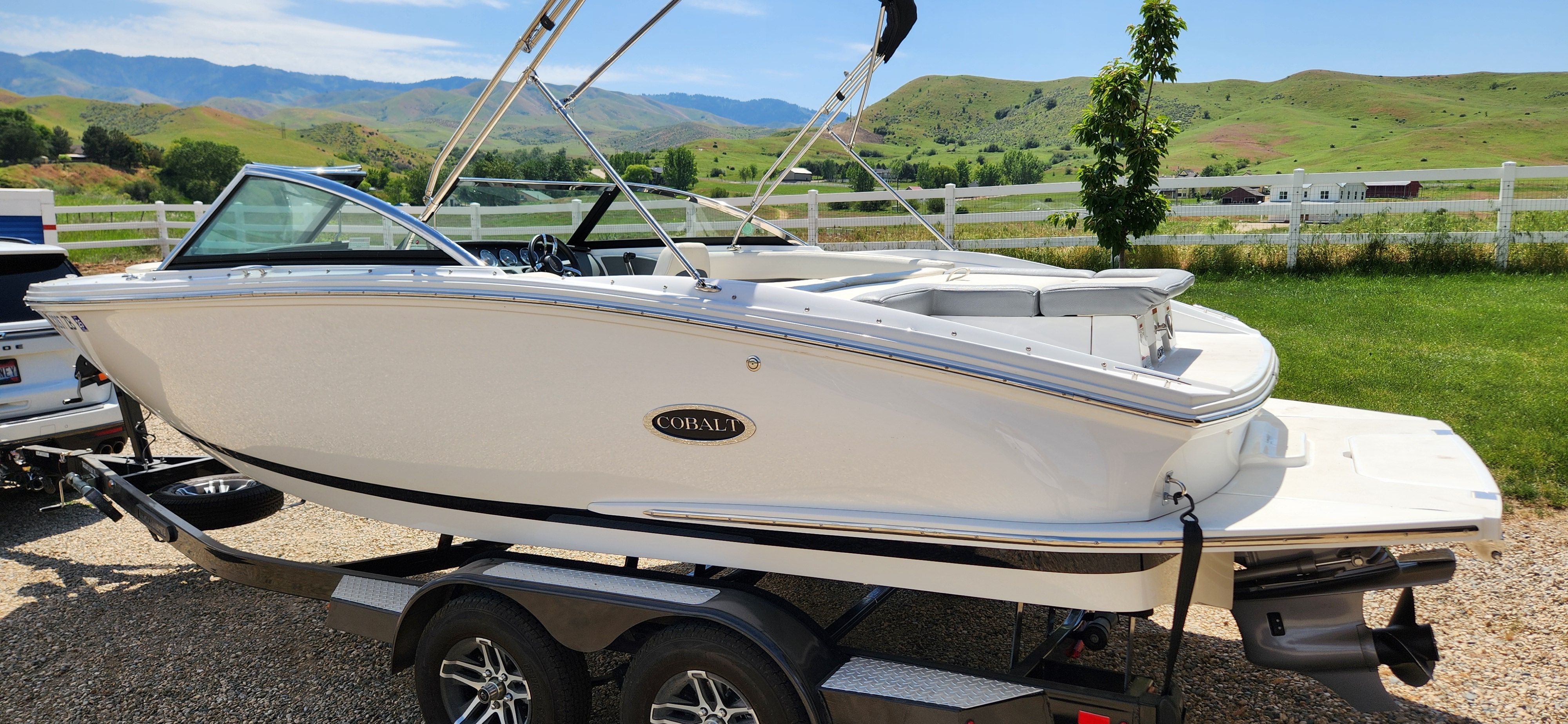 A white Cobalt CS22 boat is on a trailer in a scenic landscape.