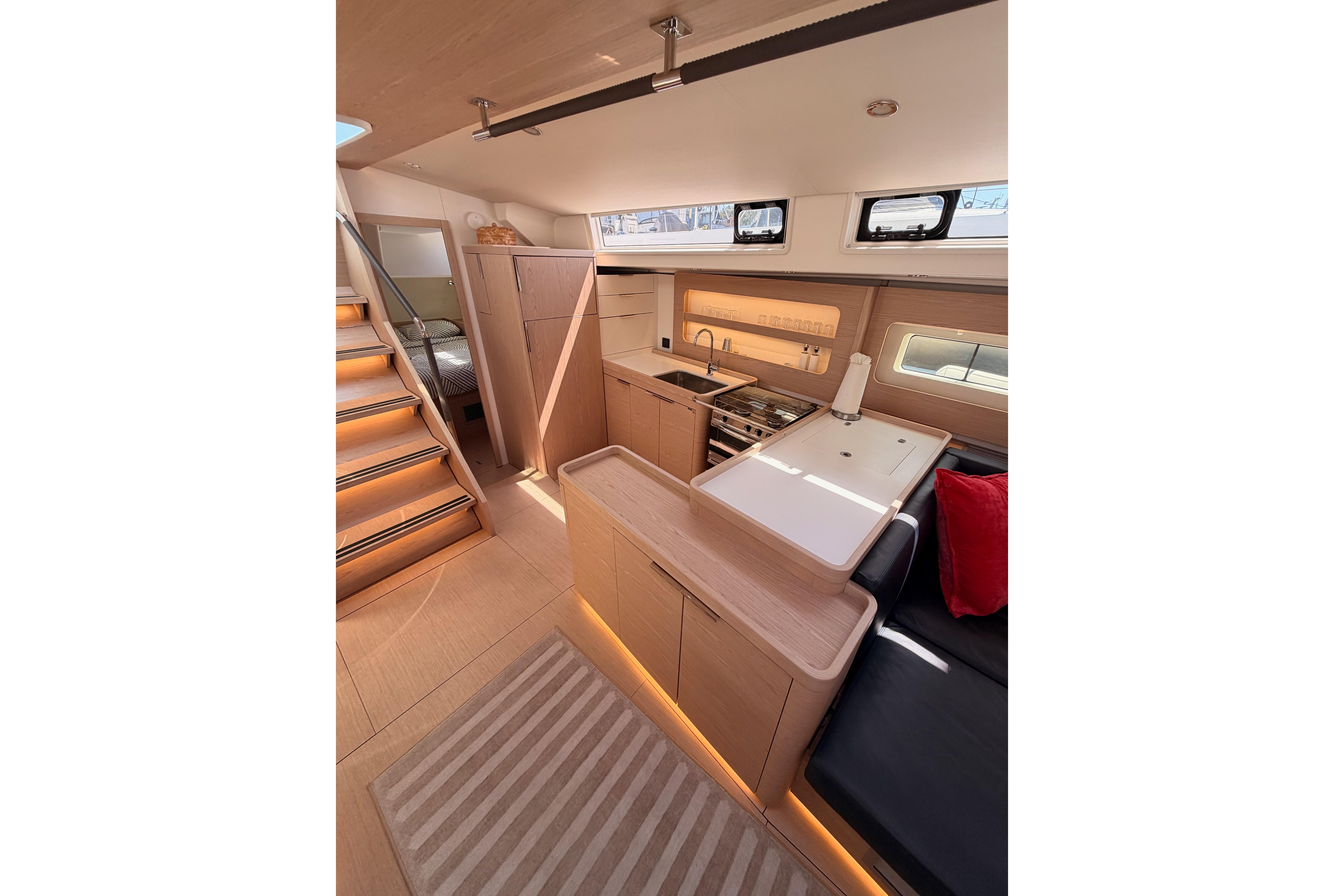 Luxurious interior of 2022 Beneteau Oceanis Yacht 54 with modern kitchen and cozy seating.