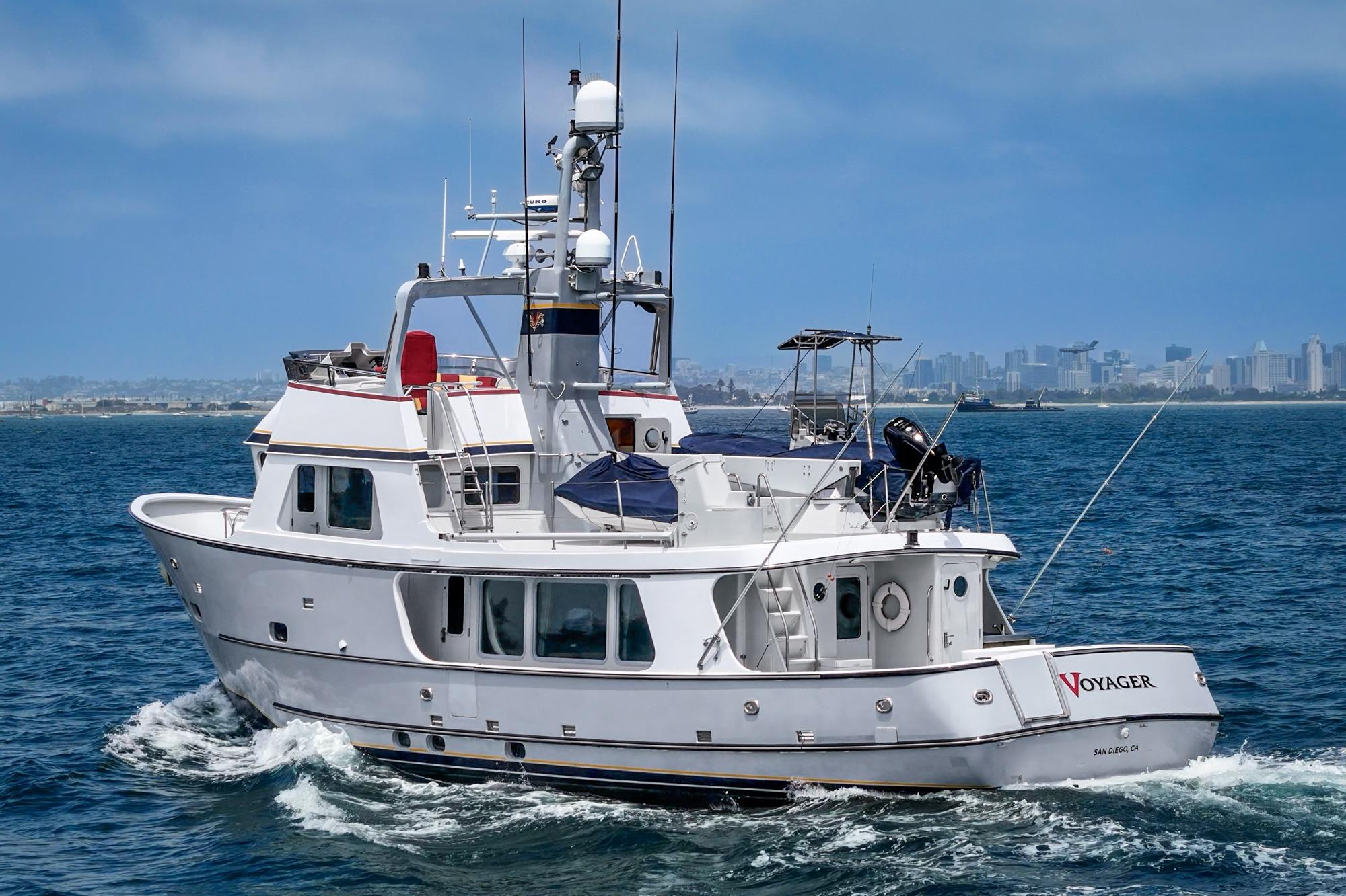A 1990 Seaton Long Range Cruiser yacht named "Voyager" sailing near a city skyline.