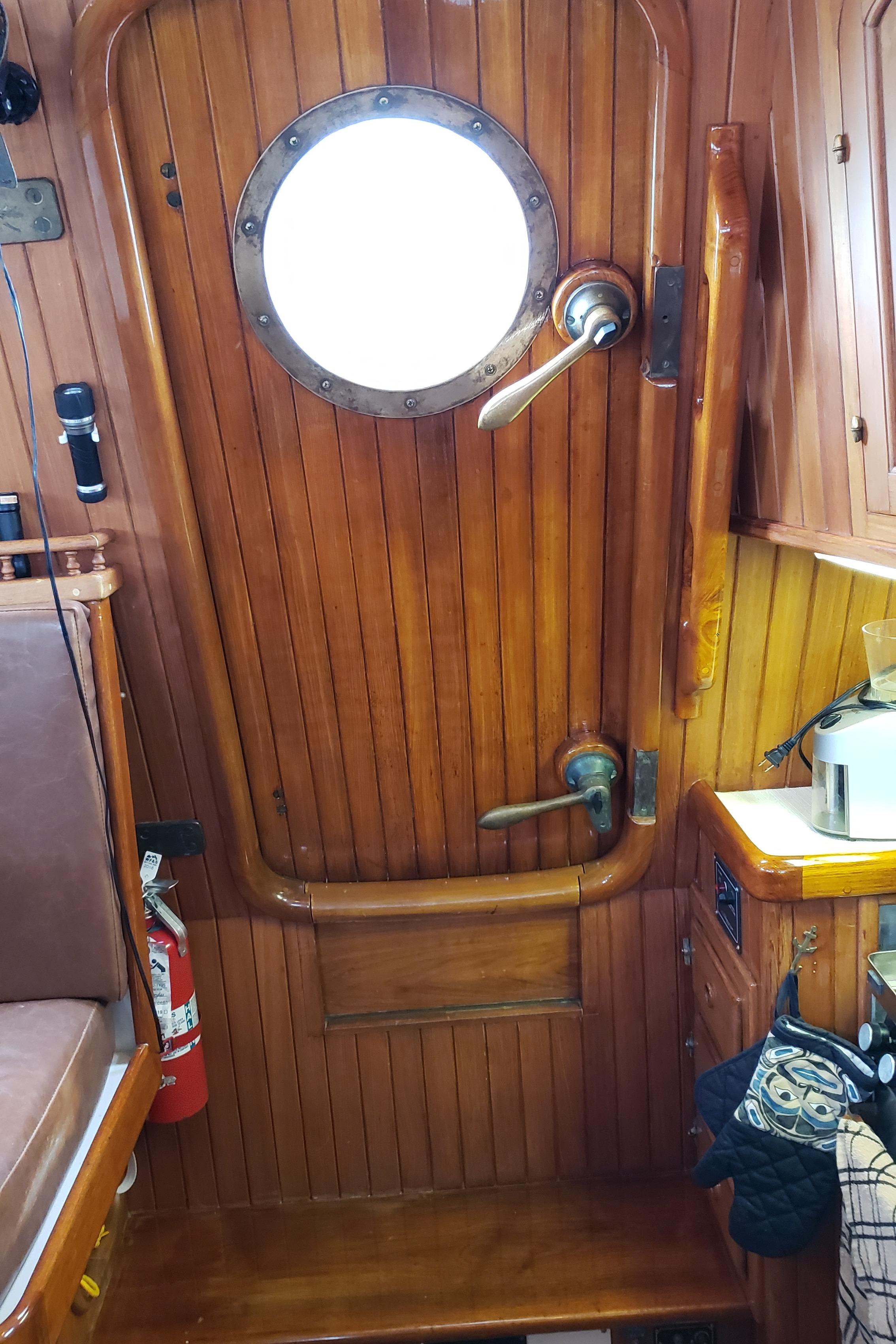 Interior of a 1983 Hans Christian 39 PH yacht with wooden door and porthole.