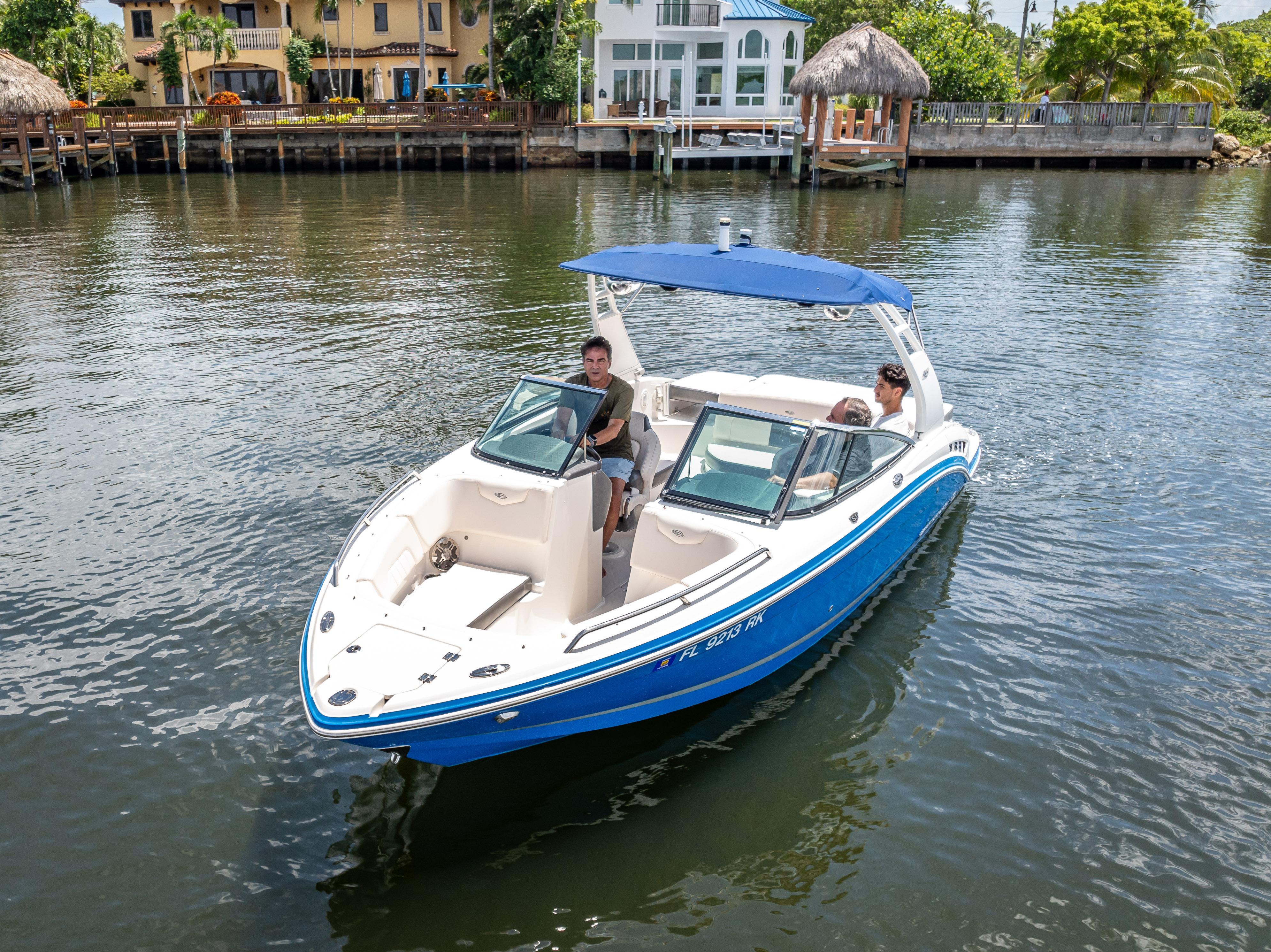 2017 Chaparral 227 SSX boat cruising on a scenic waterway with waterfront homes.