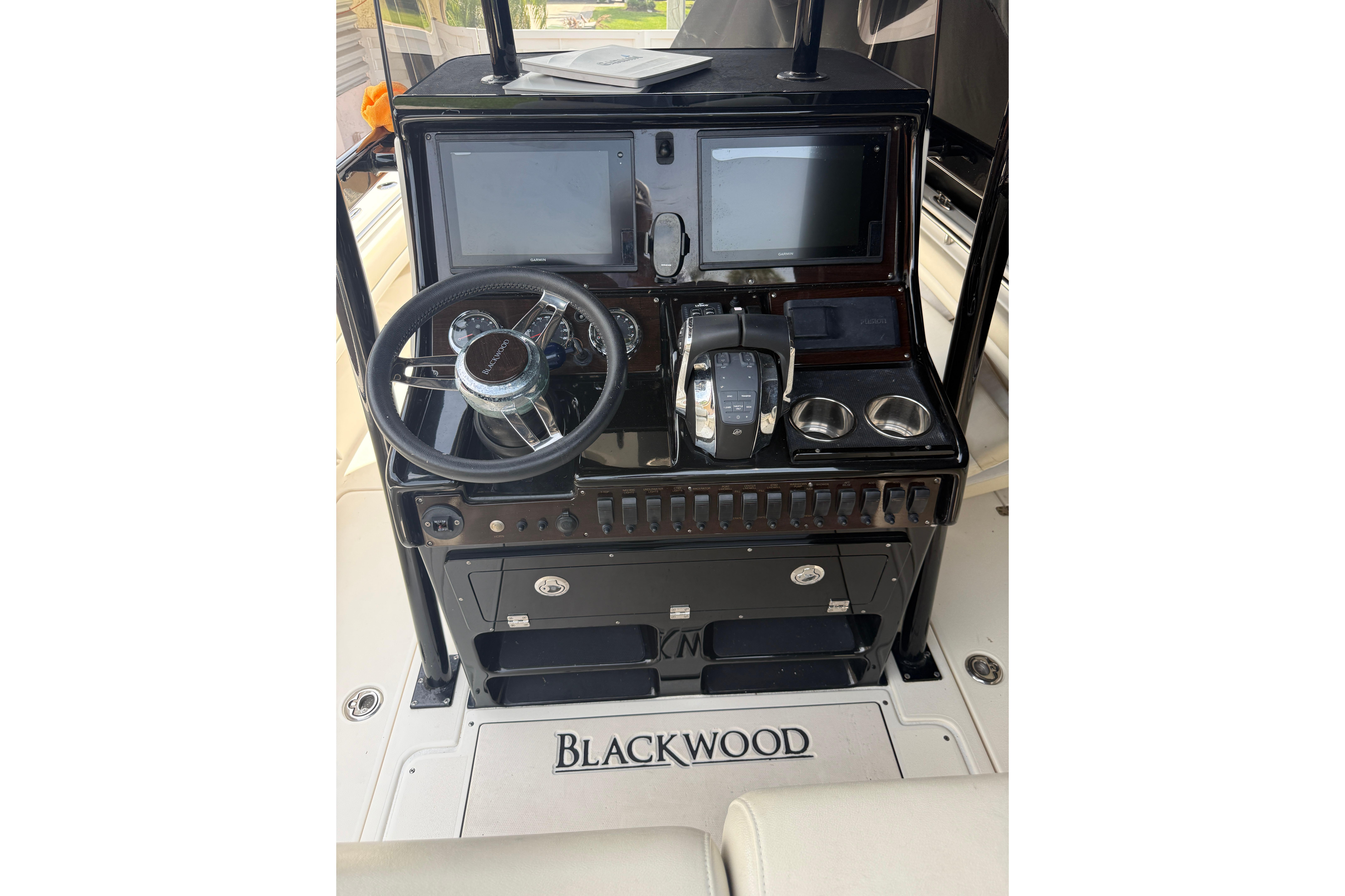 Control panel of a 2015 Blackwood 27 boat with steering wheel and displays.