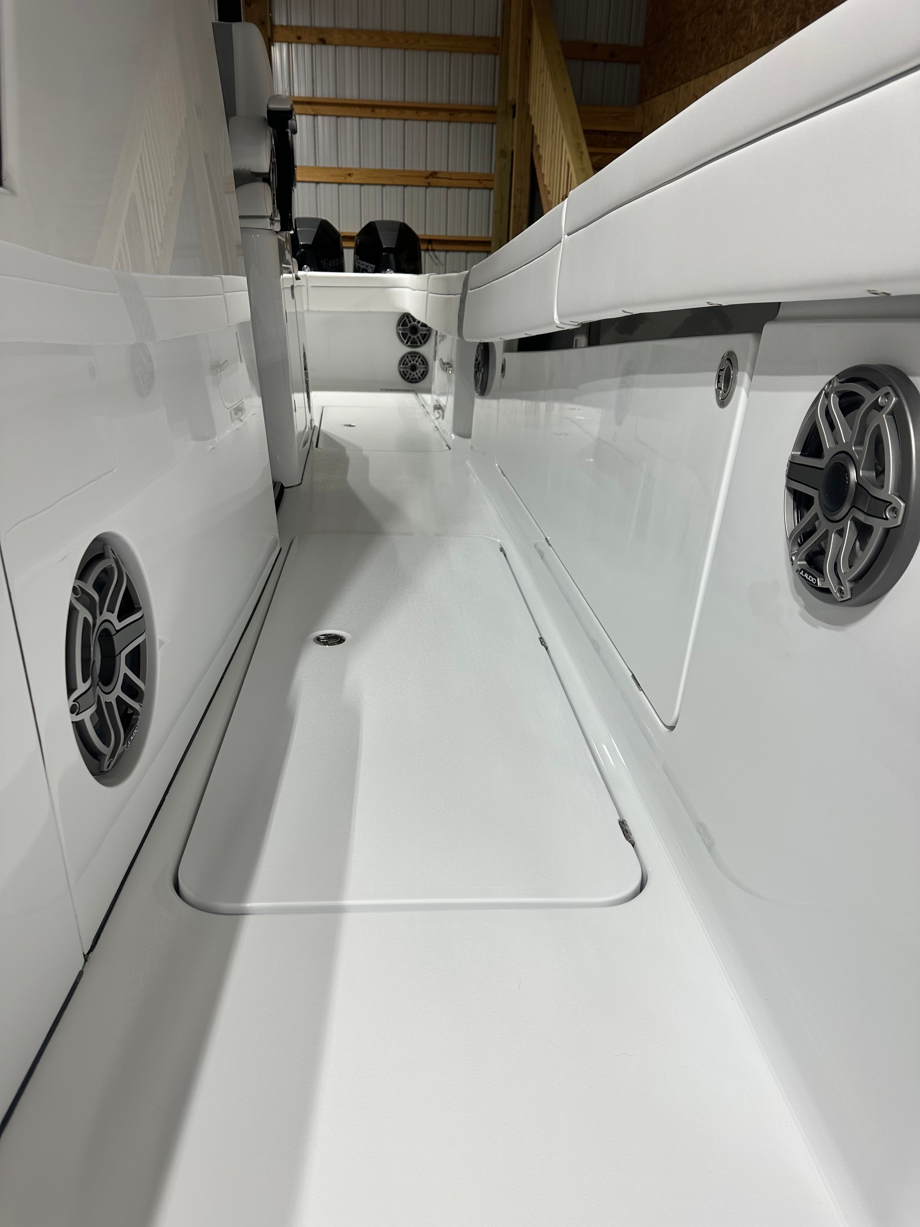 Interior view of a modern boat with white seating and speakers.