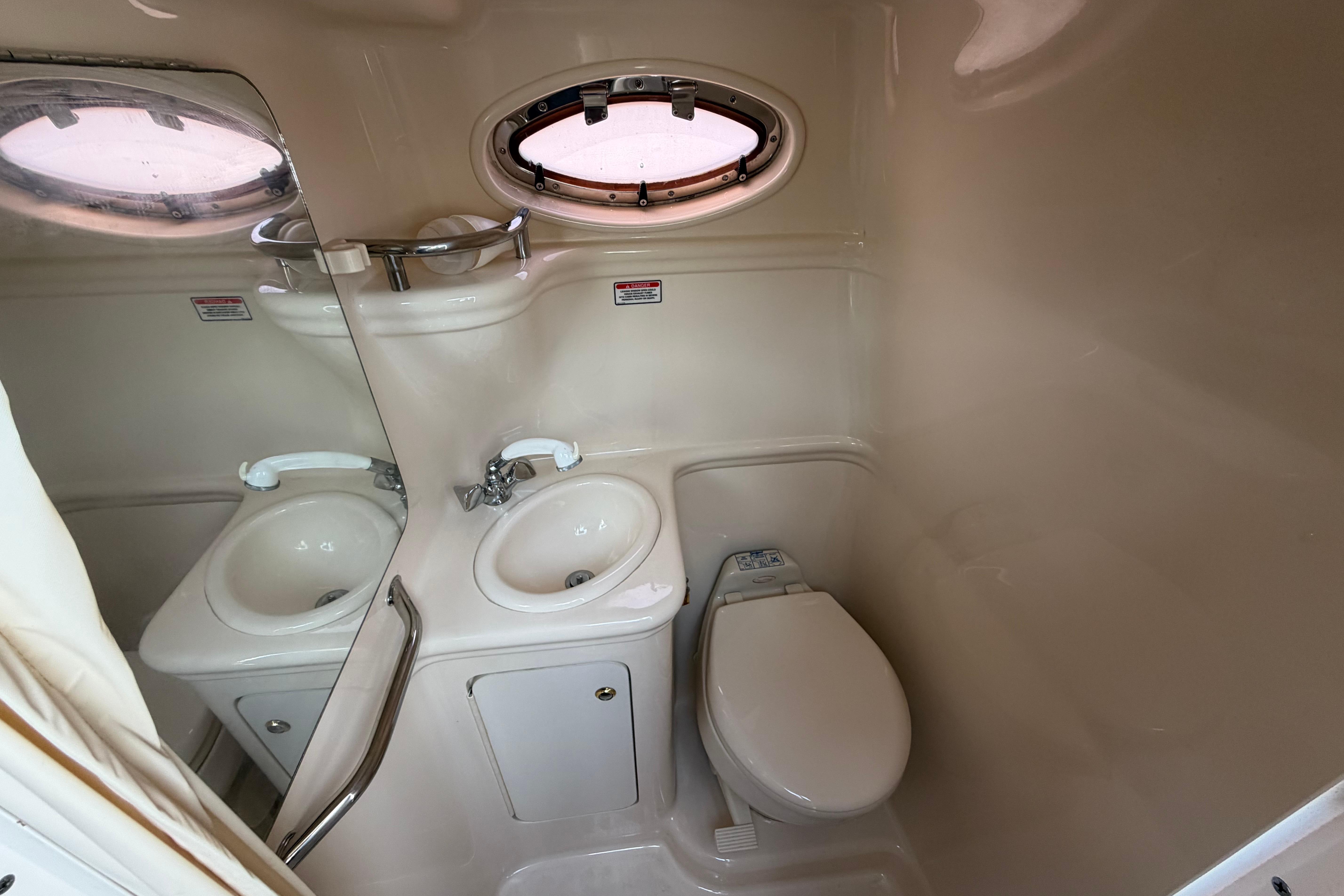 Compact bathroom in 2004 Sea Ray Sundancer 260 boat with sink and toilet.