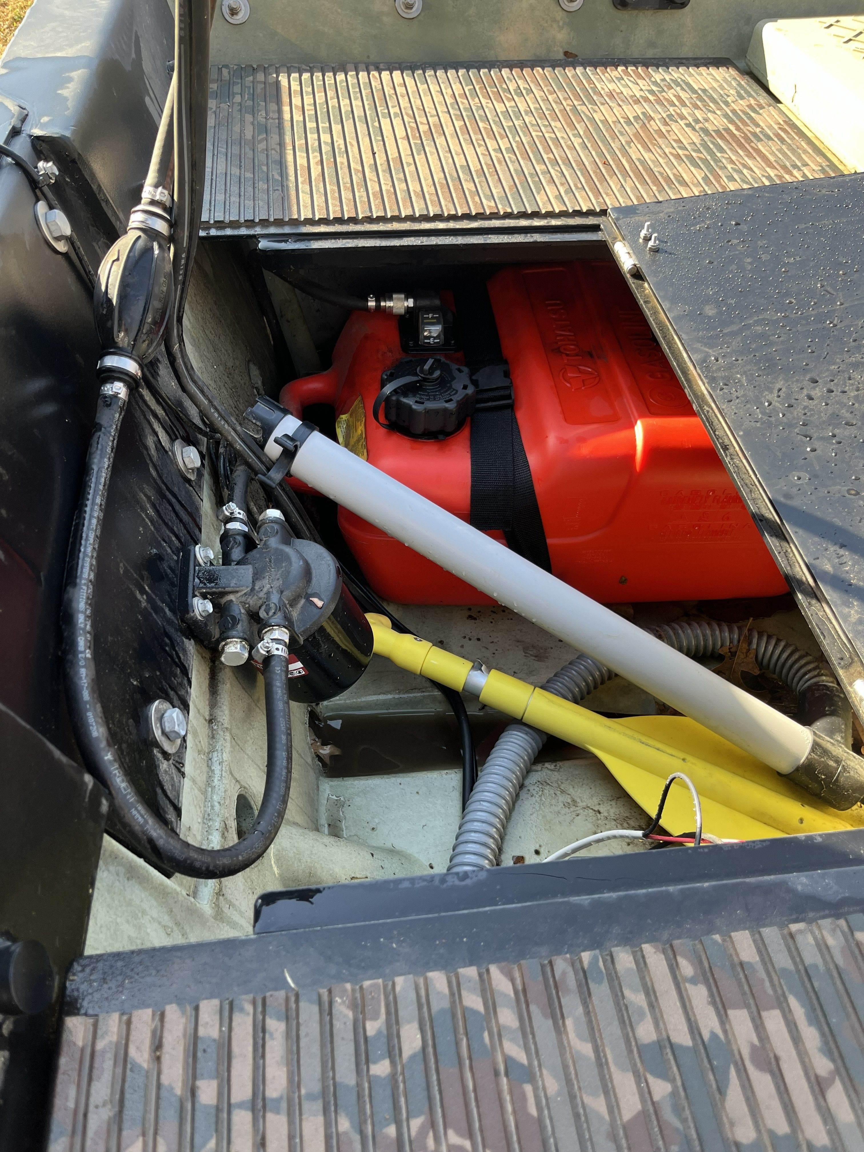 An open boat with a red fuel tank and cables inside.