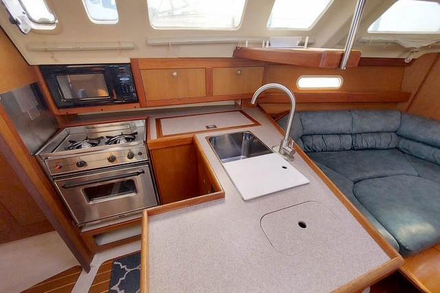 1998 Hunter 340 yacht interior kitchen with stove, sink, and seating area.