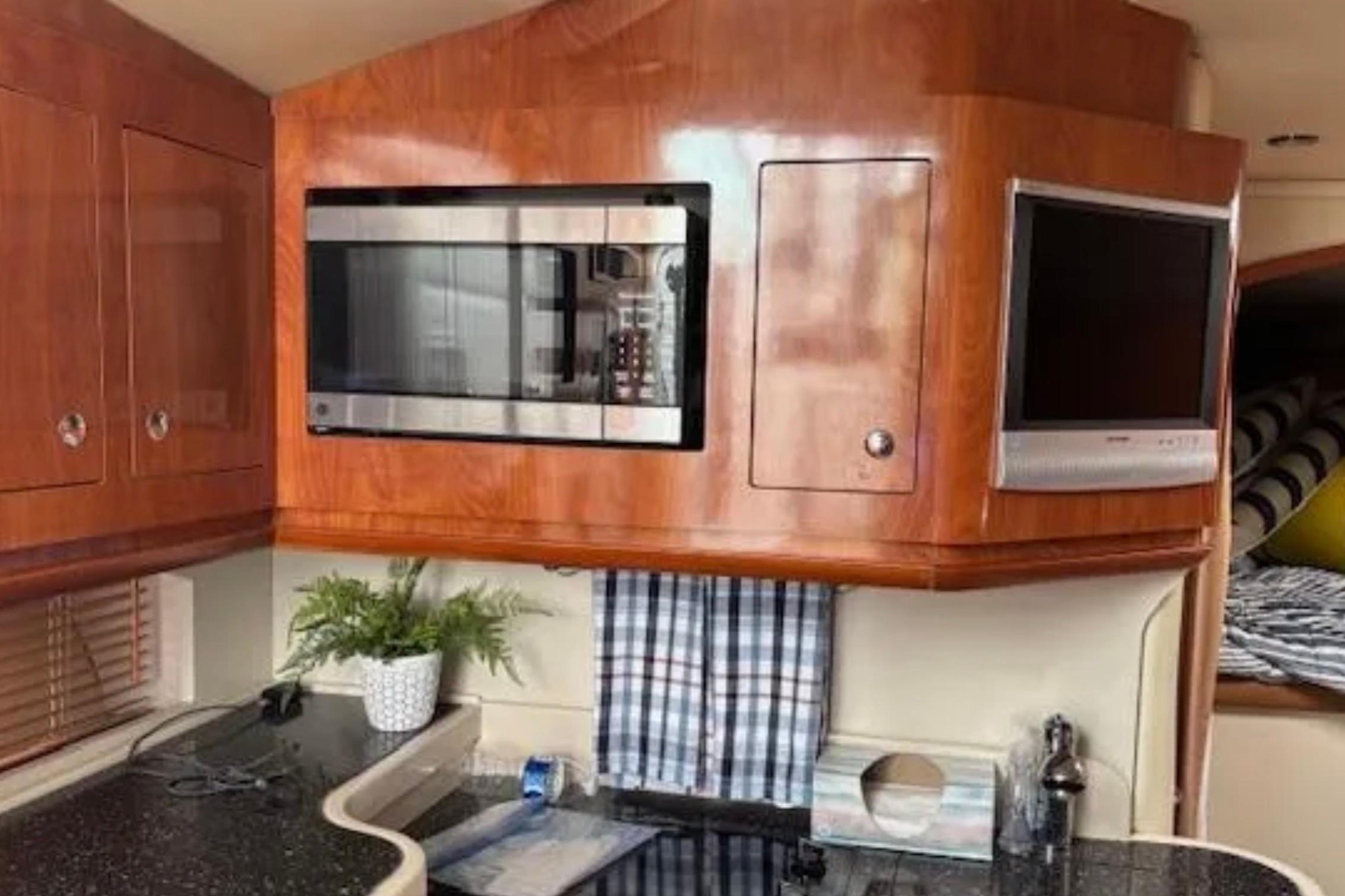 Interior of 2007 Four Winns 378 Vista yacht with microwave and TV in wooden cabinetry.