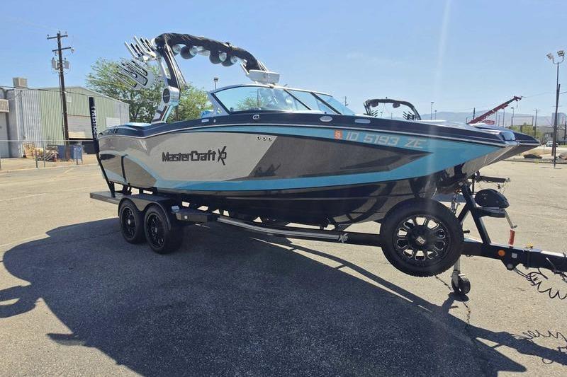 2017 MasterCraft X23 boat on trailer in parking lot, sunny day.