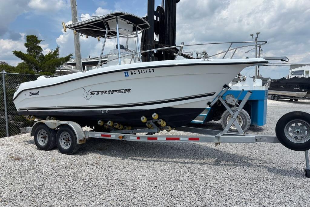 2002 Seaswirl Striper 2101 Center Console boat on trailer, parked on gravel lot.