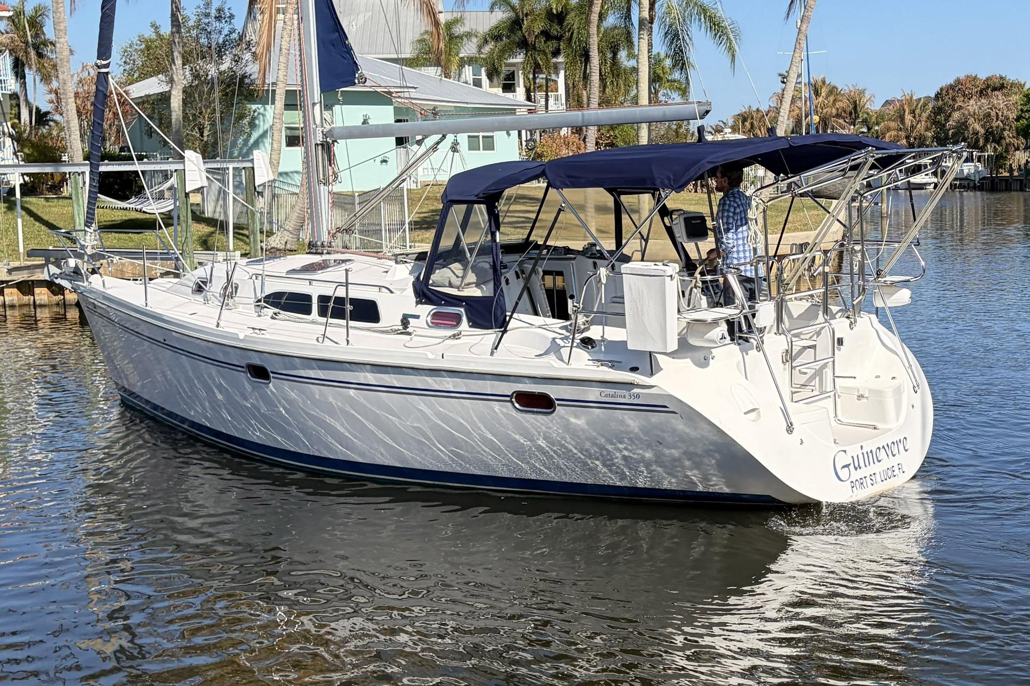 2004 Catalina 36 MkII sailboat on calm water, featuring blue canopy and sleek design.