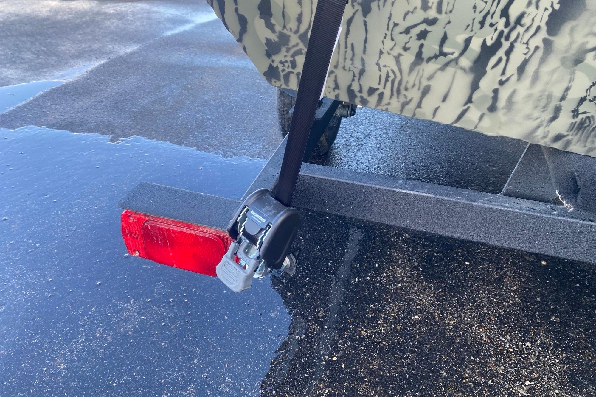 2026 Tracker Grizzly 1860 Utility trailer hitch with red reflector on wet pavement.