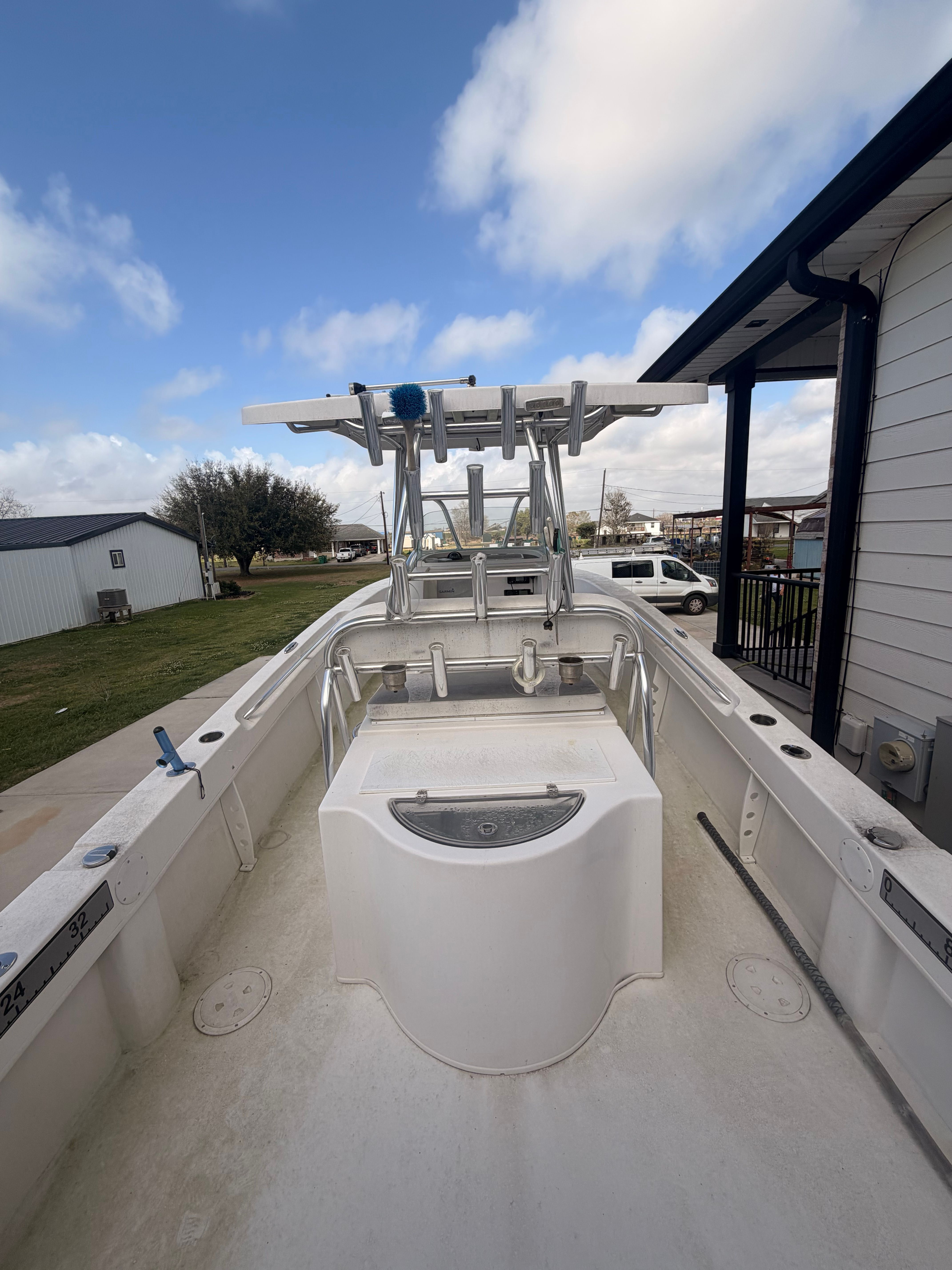 A Twin Vee Ocean Cat boat is on a trailer next to a building.