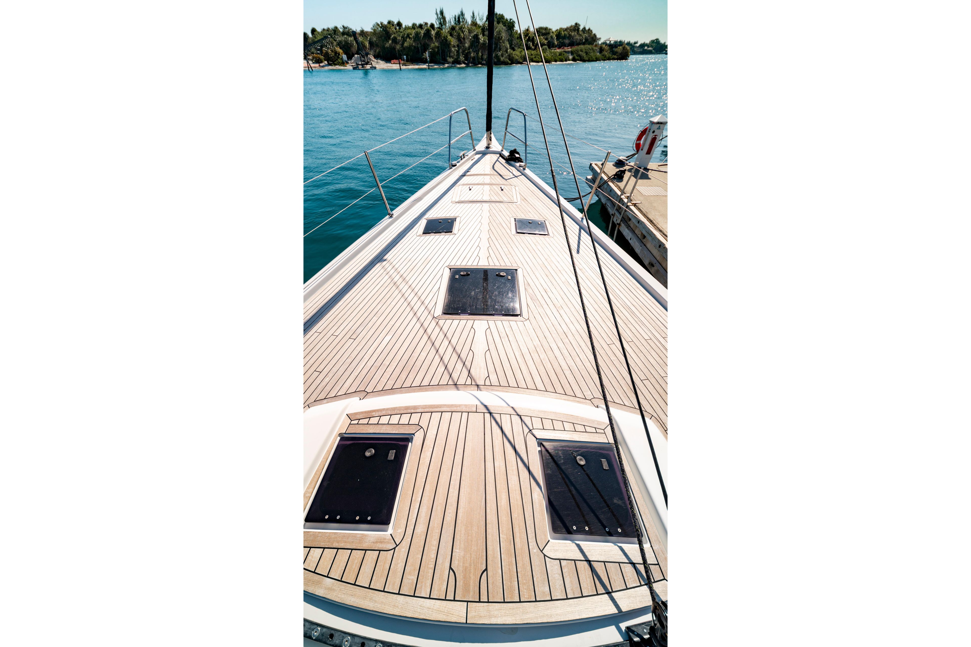 Deck view of 2016 Grand Soleil 58 yacht, docked by serene blue waters.