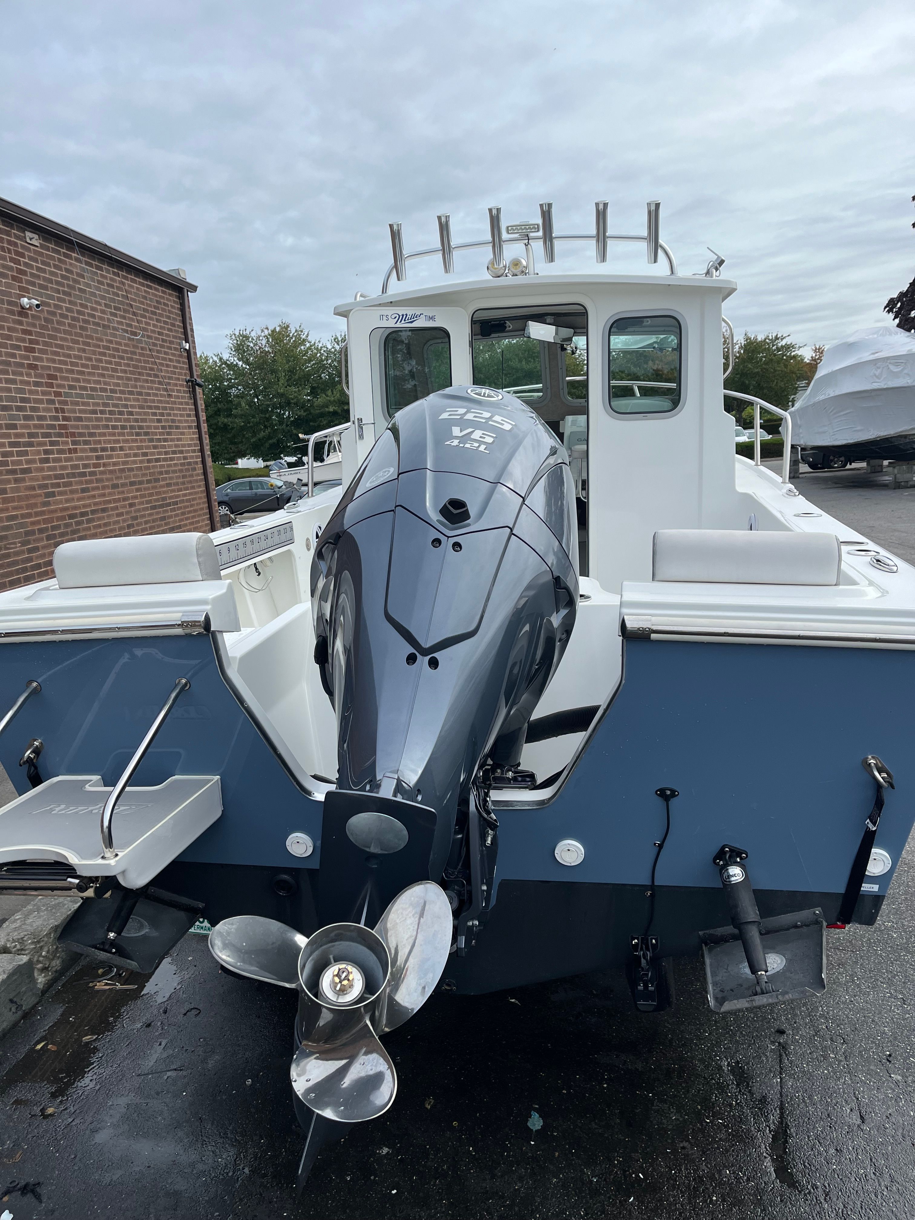 A 2021 Parker Sport Cabin boat with an outboard motor, parked in a lot.
