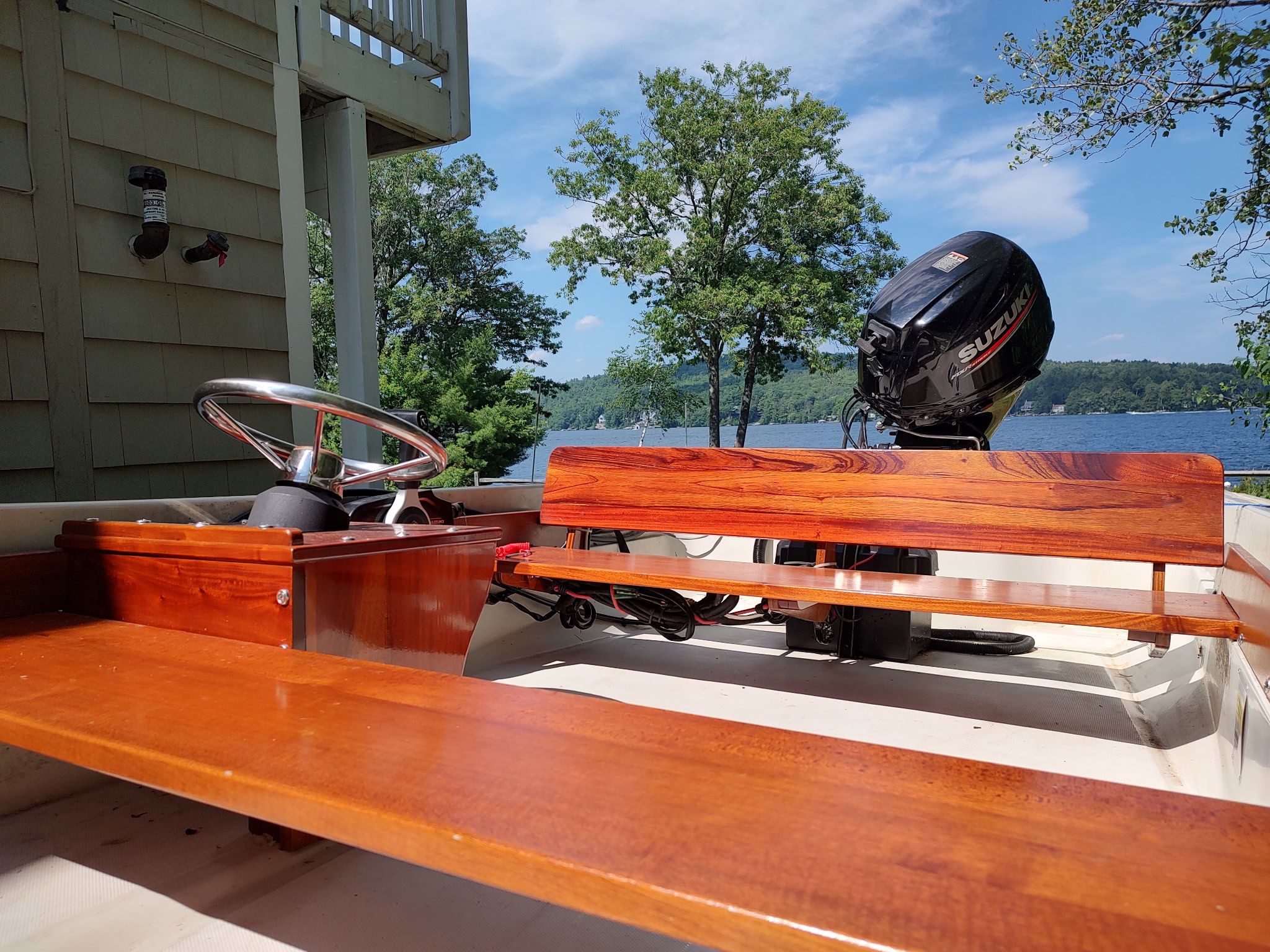 A 1987 Boston Whaler Sport 13 with wooden seats and an outboard motor, by the lakeside.