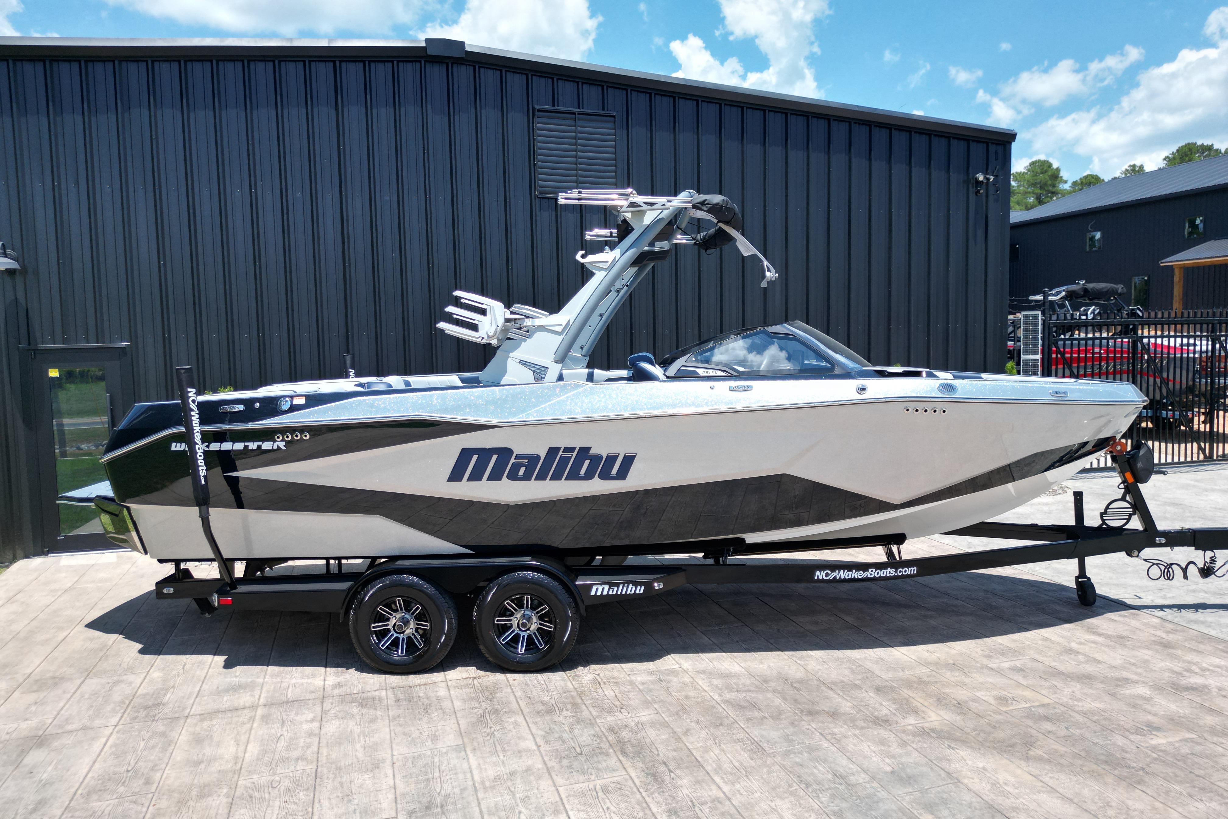 2025 Malibu Wakesetter 25 LSV boat on trailer, parked outside a black building.