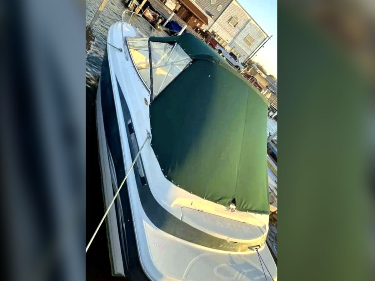 A 1999 Maxum 2300CC boat with a green cover, docked at a pier.