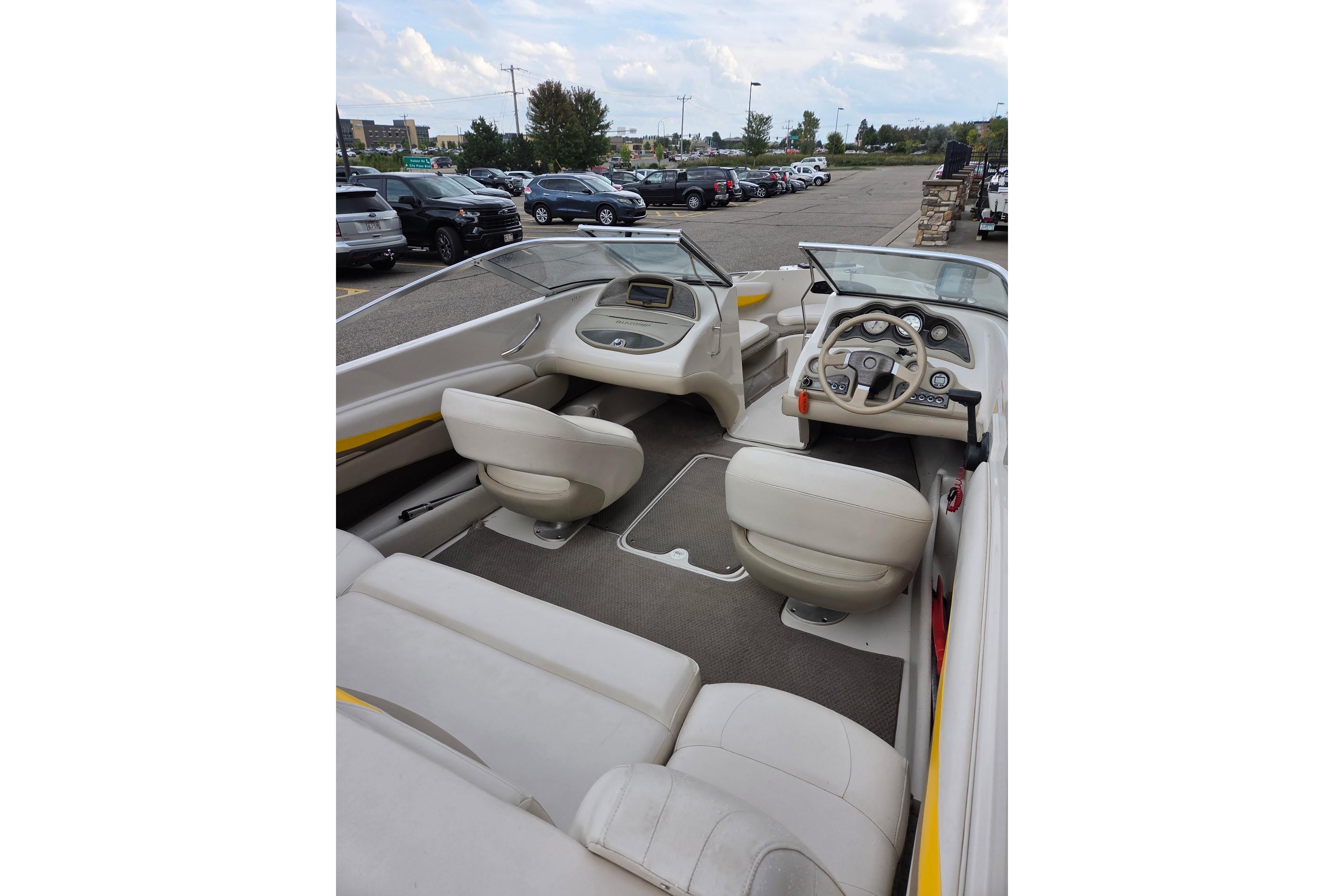 2003 Glastron GX185SF boat interior with beige seating and dashboard, parked in a lot.