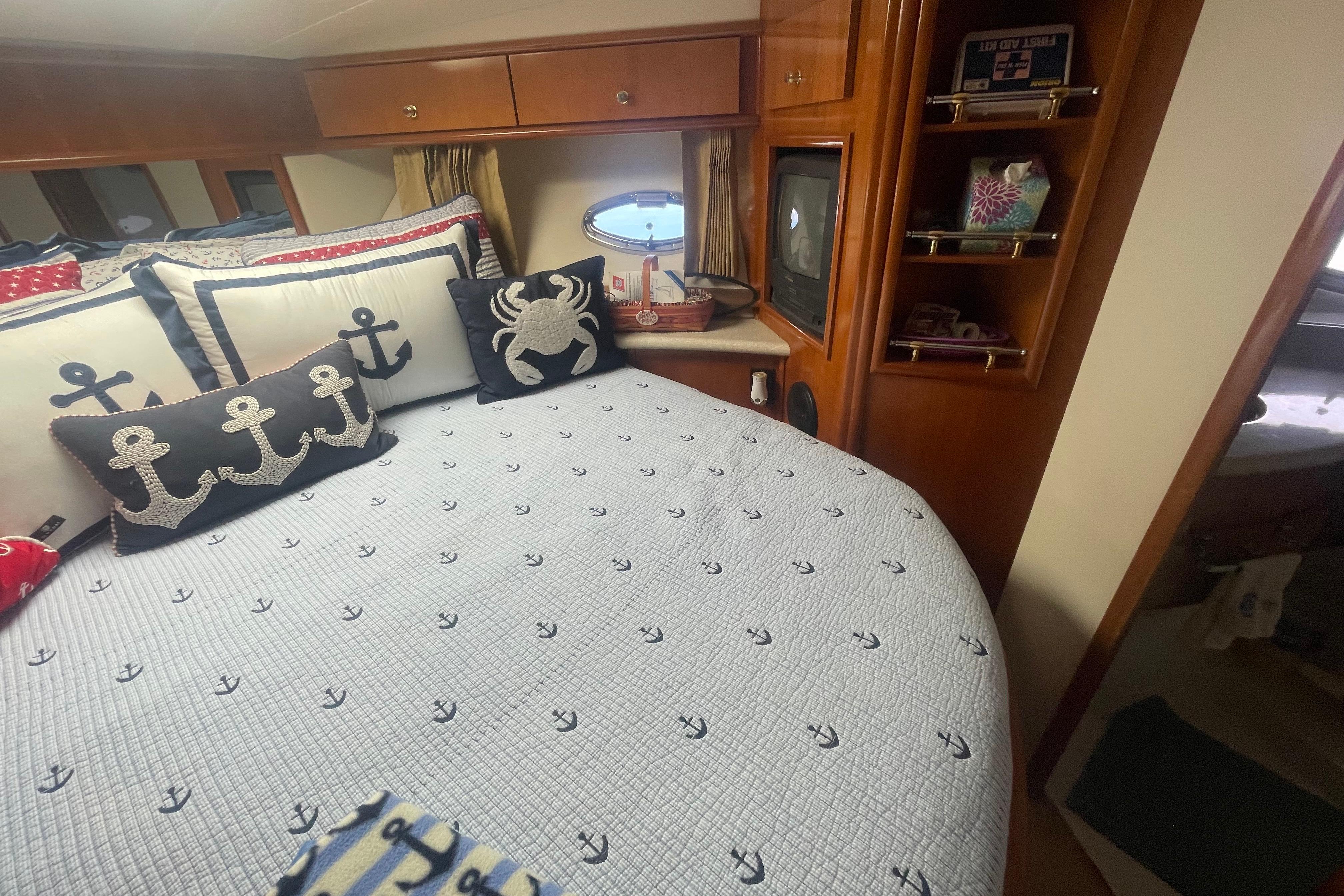 Nautical-themed bedroom in 2002 Carver 410 Sport Sedan with anchor pillows and cozy decor.