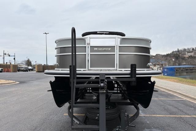 2025 Ranger Reata 243C pontoon boat on trailer, parked in a lot near water.