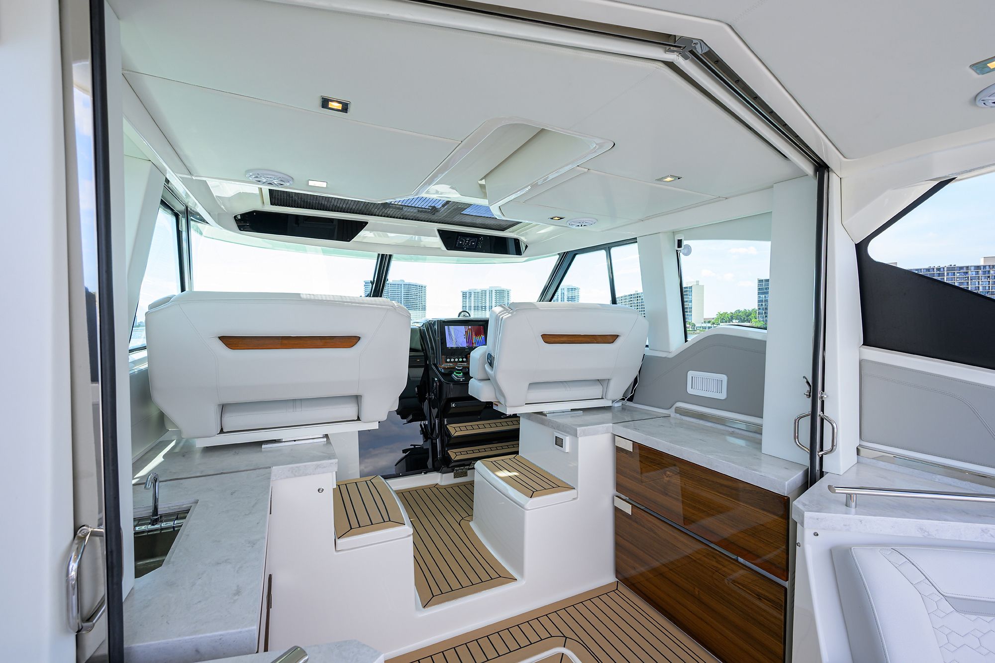 Interior of a modern yacht with white seats and wood accents.