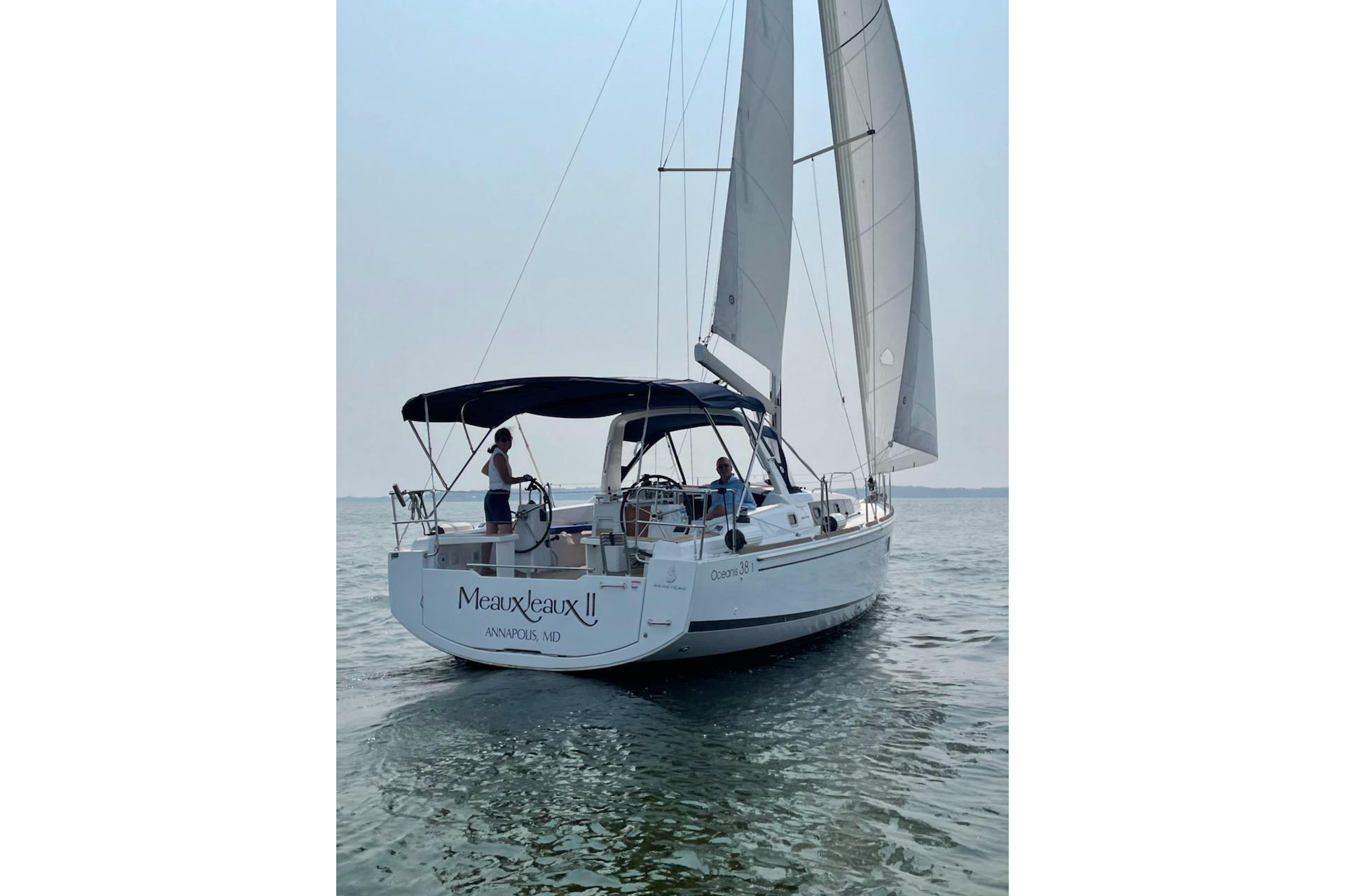 2021 Beneteau Oceanis 38.1 sailboat on calm water, rear view with sails up.