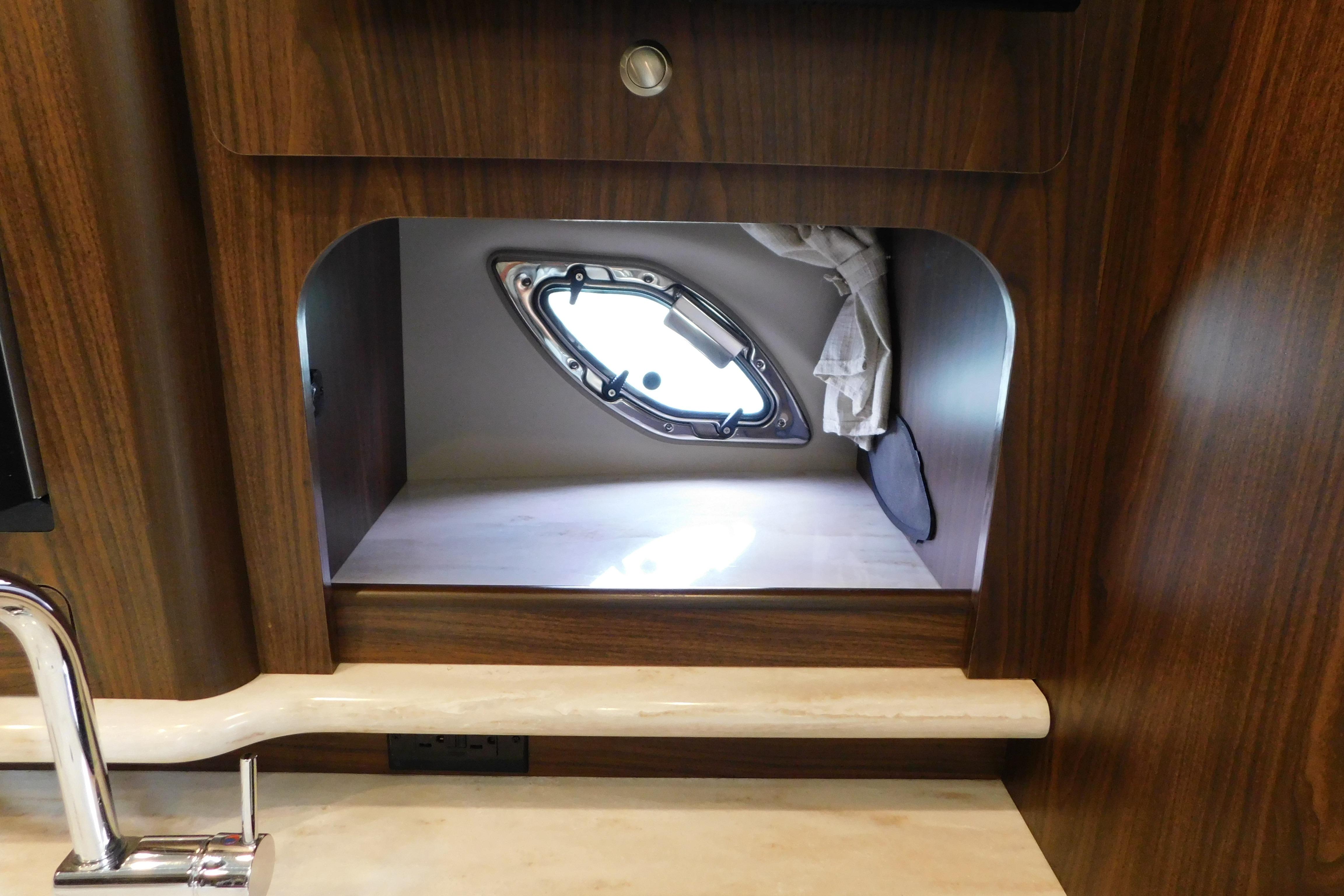 Interior of 2017 Rinker EX 320 boat with wooden cabinetry and porthole window.