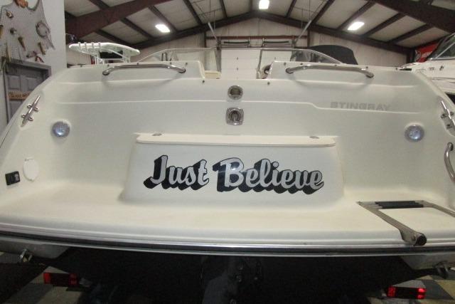 2004 Stingray 240 LR boat with "Just Believe" text on the stern in a warehouse.
