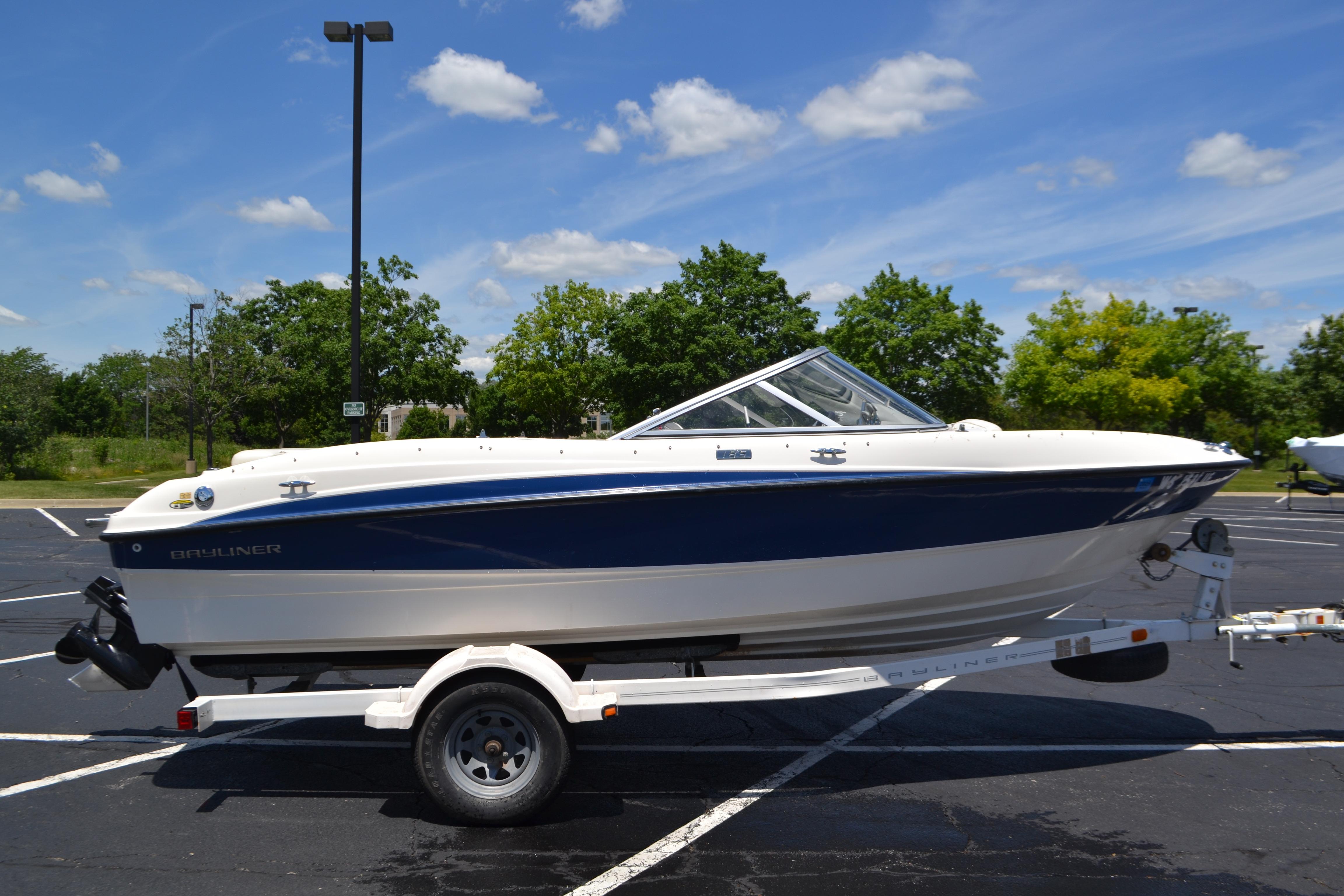 2009 Bayliner 185 Bowrider boat on trailer in parking lot, sunny day.