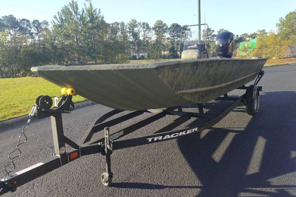 2026 Tracker Grizzly 2072 CC boat on trailer, parked on asphalt near grassy area.